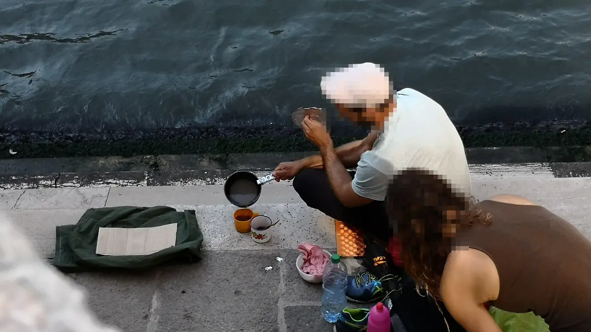 HANDOUT - 19.07.2019, Italien, Venedig: Zwei deutsche Touristen sitzen mit ihrem Gepäck an der Treppe der Rialto-Brücke und kochen sich mit einem kleinen Kaffeekocher einen Kaffee auf dem Gehweg. (zu dpa "Deutsche Touristen kochen Kaffee in Venedig - fast 1000 Euro Strafe") Foto: Comune di Venezia/dpa - ACHTUNG: Nur zur redaktionellen Verwendung im Zusammenhang mit der aktuellen Berichterstattung und nur mit vollständiger Nennung des vorstehenden Credits +++ dpa-Bildfunk +++