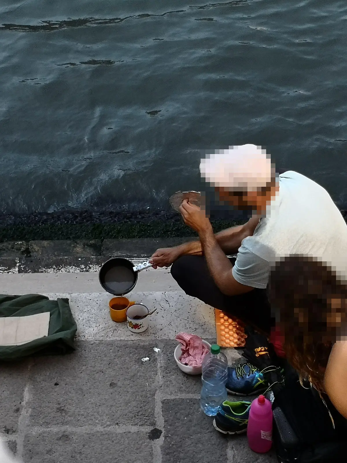 HANDOUT - 19.07.2019, Italien, Venedig: Zwei deutsche Touristen sitzen mit ihrem Gepäck an der Treppe der Rialto-Brücke und kochen sich mit einem kleinen Kaffeekocher einen Kaffee auf dem Gehweg. (zu dpa "Deutsche Touristen kochen Kaffee in Venedig - fast 1000 Euro Strafe") Foto: Comune di Venezia/dpa - ACHTUNG: Nur zur redaktionellen Verwendung im Zusammenhang mit der aktuellen Berichterstattung und nur mit vollständiger Nennung des vorstehenden Credits +++ dpa-Bildfunk +++