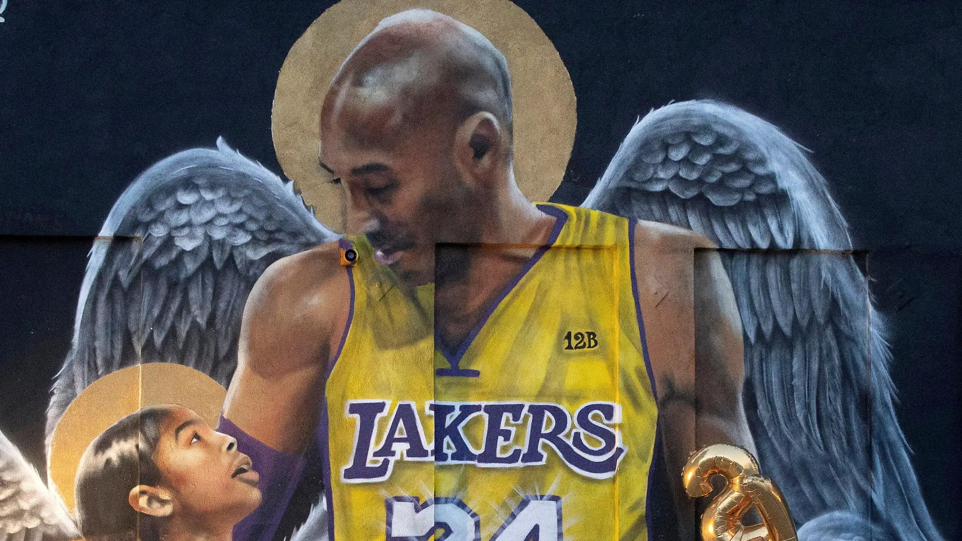 FILE PHOTO: FILE PHOTO: A fan poses by a mural of late Kobe Bryant, who perished one year ago alongside his daughter and seven others when their helicopter crashed into a hillside, in Los Angeles, California, U.S., January 26, 2021. REUTERS/Mario Anzuoni/File Photo/File Photo