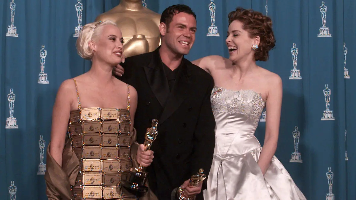 Lizzy Gardiner and Tim Chappel hold their Oscars for Costume Design for the film "The Adventures of Pricilla, Queen of the Desert" along with presenter Sharon Stone in this March 27, 1995 photo. American Express, who originally gave Gardiner 254 gold cards to creat the dress, has bought back the gown for an undisclosed price. (AP Photo/Lois Berstein)