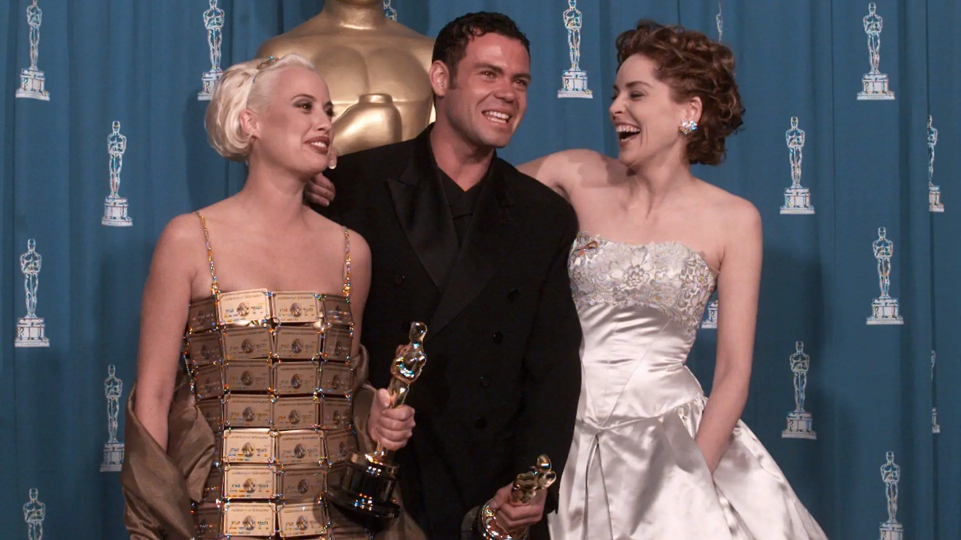 Lizzy Gardiner and Tim Chappel hold their Oscars for Costume Design for the film "The Adventures of Pricilla, Queen of the Desert" along with presenter Sharon Stone in this March 27, 1995 photo. American Express, who originally gave Gardiner 254 gold cards to creat the dress, has bought back the gown for an undisclosed price. (AP Photo/Lois Berstein)