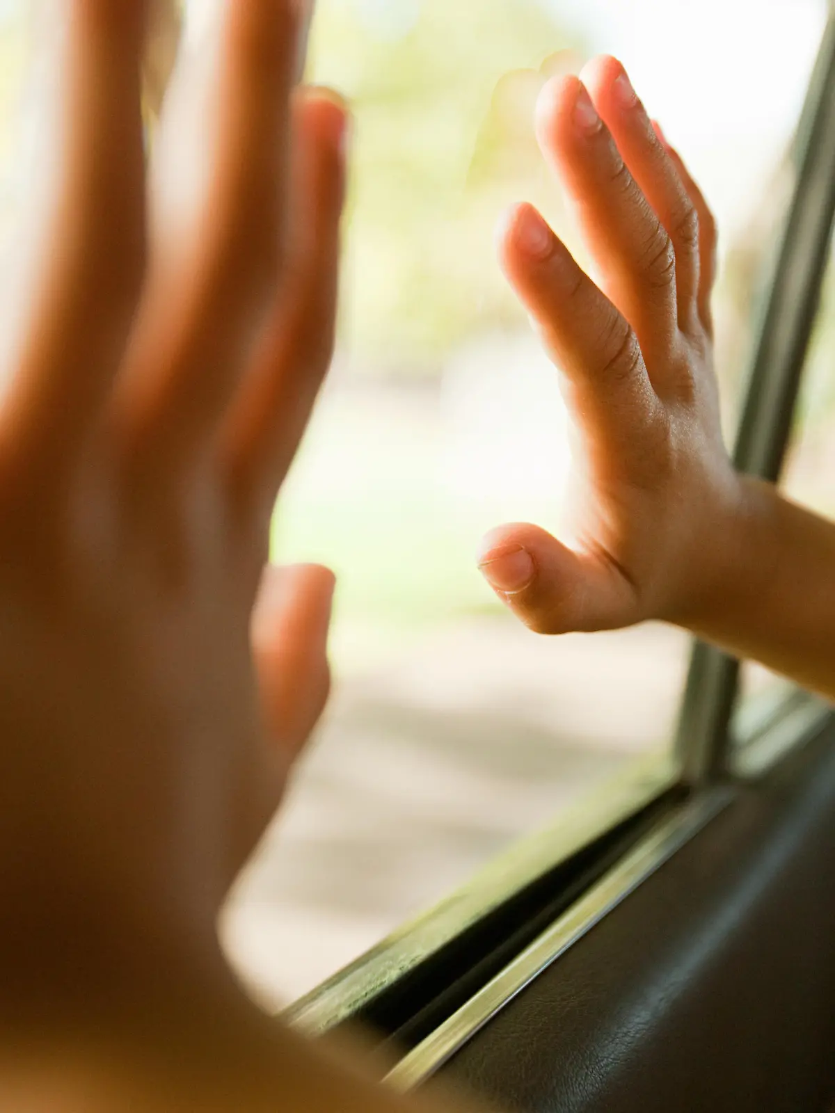 Kinderhände berühren ein Autofenster.
