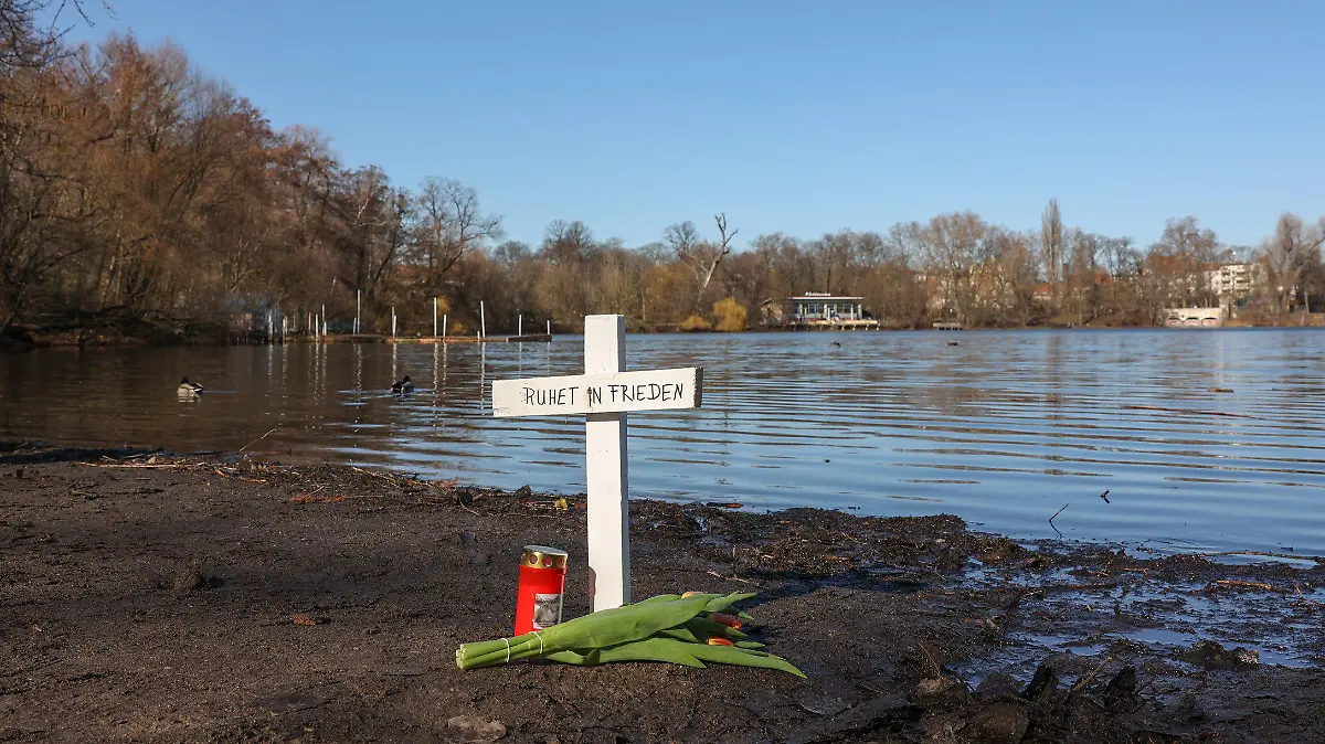 28.02.2023, Berlin: Nach dem Fund zweier Leichen im Weißen See sind an dem Fundort ein Kreuz, Blumen und eine Kerze zu sehen. Foto: Jörg Carstensen/dpa +++ dpa-Bildfunk +++