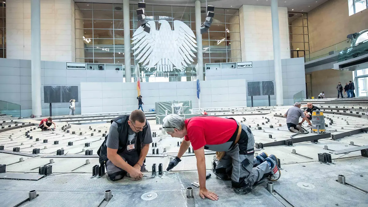 dpatopbilder - 08.07.2019, Berlin: Handwerker entfernen die Kleberreste auf dem Boden im Plenarsaal im Deutschen Bundestag. In der Sommerpause wird der Teppich ausgetauscht, die Brandmeldeanlage erneuert und eine Induktionsschleife für Hörgeräteträger installiert. Foto: Michael Kappeler/dpa +++ dpa-Bildfunk +++