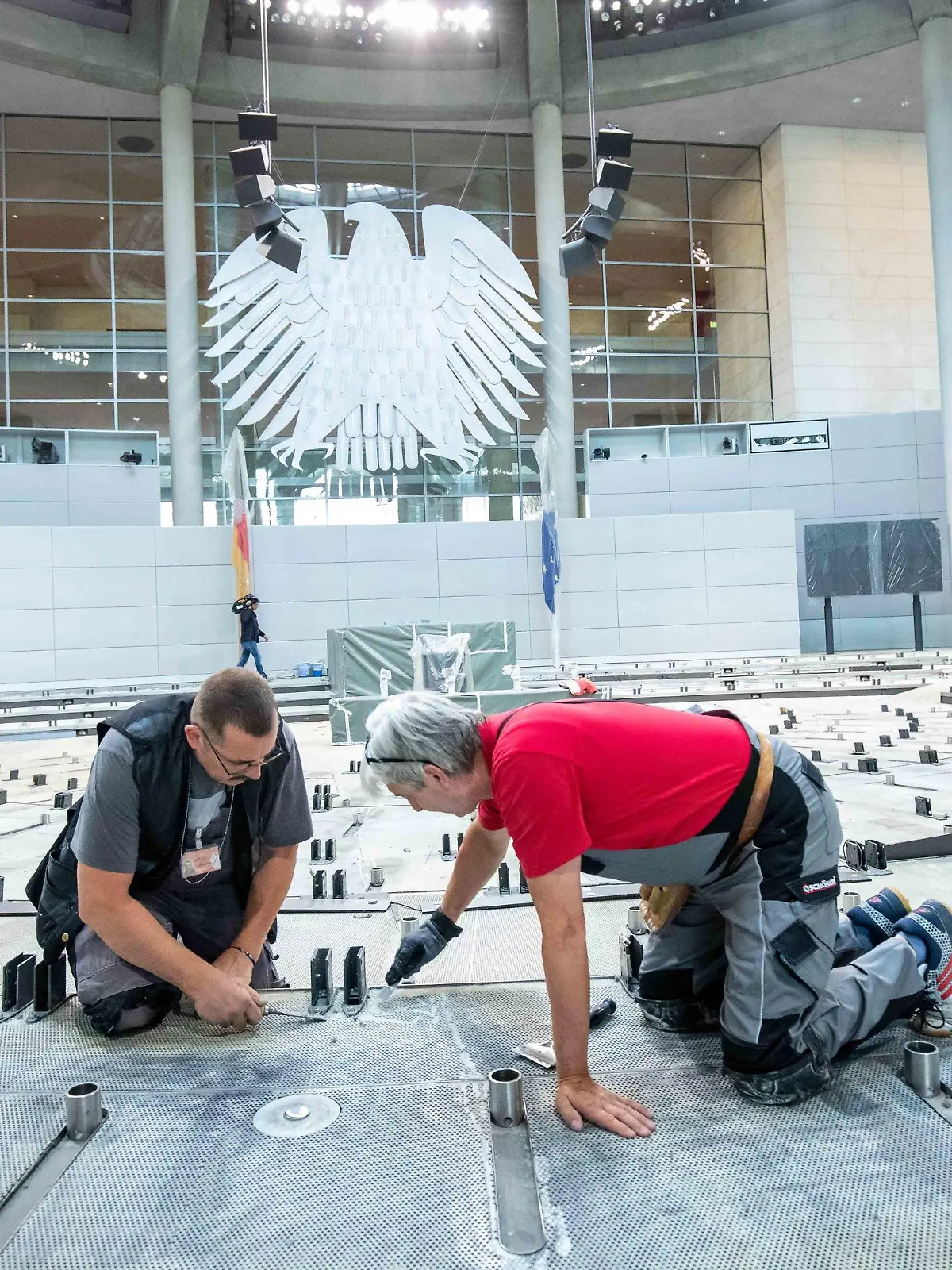 dpatopbilder - 08.07.2019, Berlin: Handwerker entfernen die Kleberreste auf dem Boden im Plenarsaal im Deutschen Bundestag. In der Sommerpause wird der Teppich ausgetauscht, die Brandmeldeanlage erneuert und eine Induktionsschleife für Hörgeräteträger installiert. Foto: Michael Kappeler/dpa +++ dpa-Bildfunk +++