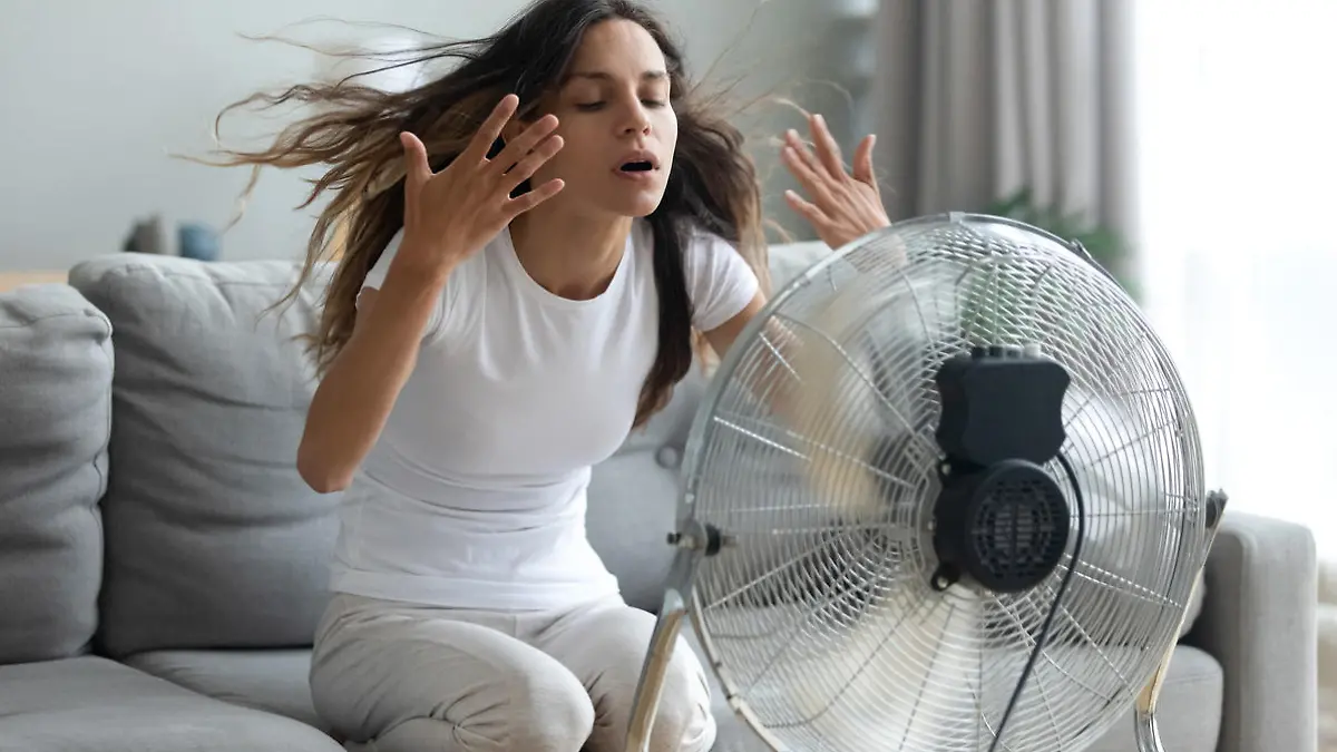 Frau kühlt sich mit Ventilator