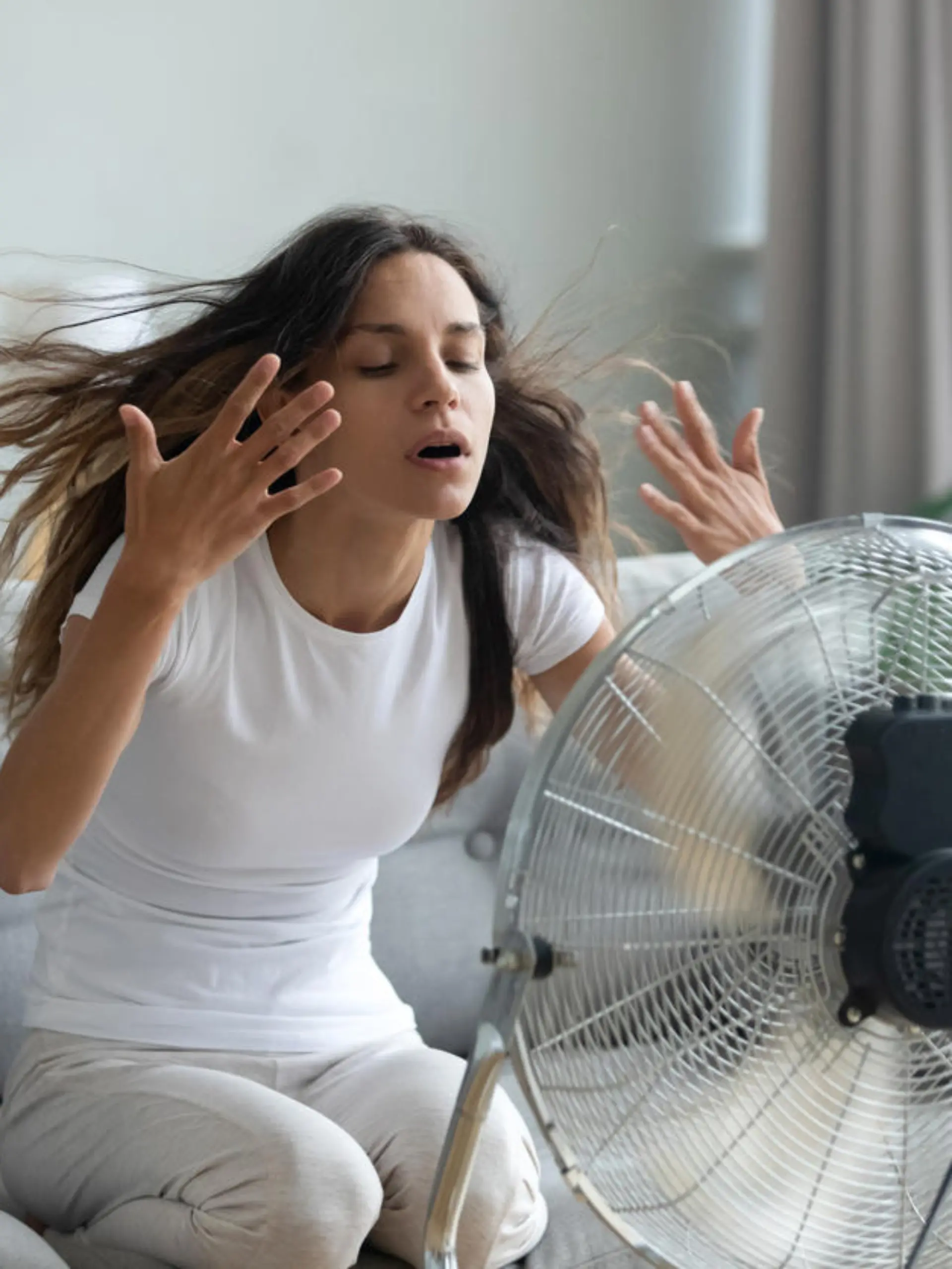 Frau kühlt sich mit Ventilator