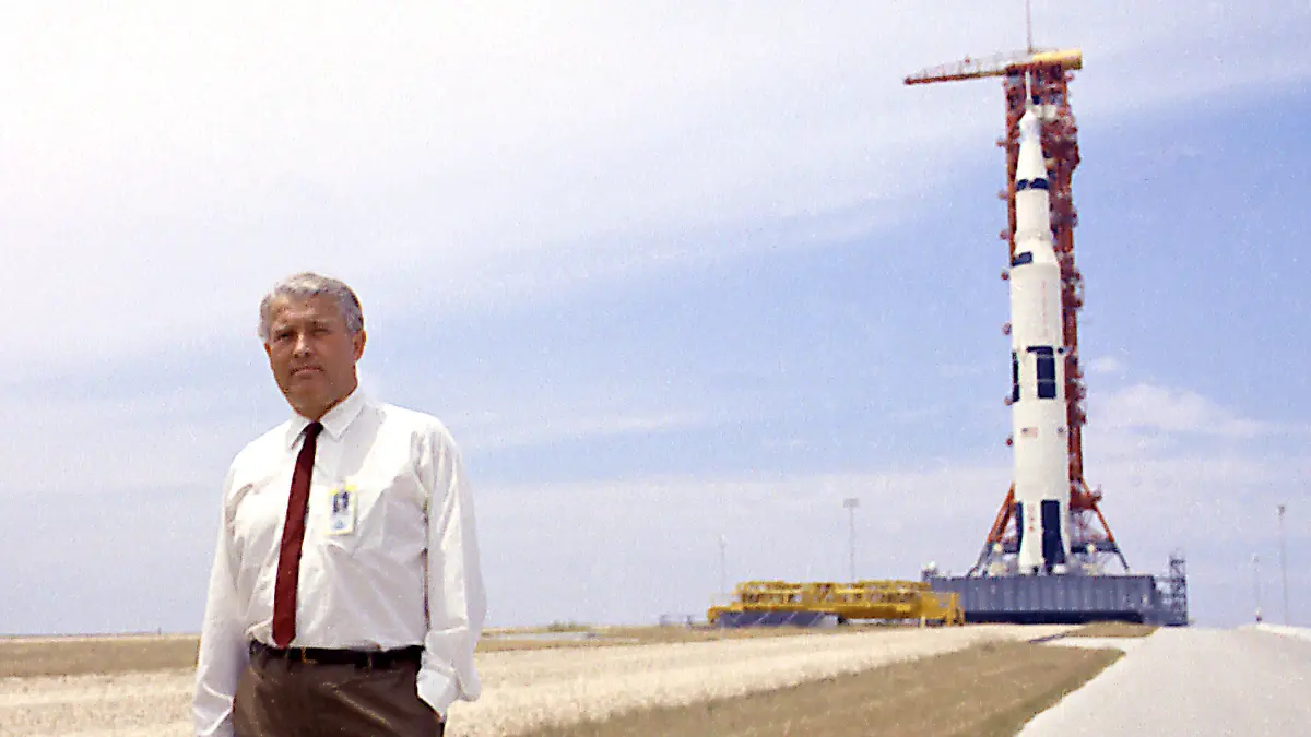 HANDOUT - 10.06.2019, USA, Cape Canaverel: Die undatierte Aufnahme zeigt Wernher von Braun, Raketenkonstrukteur aus Deutschland, der vor der Saturn-V-Trägerrakete, mit der Apollo-11-Kapsel an der Spitze, steht. 1969 wurde die amerikanische Flagge auf dem Mond gehisst. Der Erfolg der USA gründete auch auf einer Raketentechnologie, die deutsche Forscher um Wernher von Braun entwickelt hatten. Sie diente ursprünglich dem Zweck, Adolf Hitler zum Sieg zu verhelfen. (zu dpa «Von den Nazis zur Nasa: Der deutsche Anteil an der Mondlandung») Foto: -/NASA/dpa - ACHTUNG: Nur zur redaktionellen Verwendung und nur mit vollständiger Nennung des vorstehenden Credits +++ dpa-Bildfunk +++