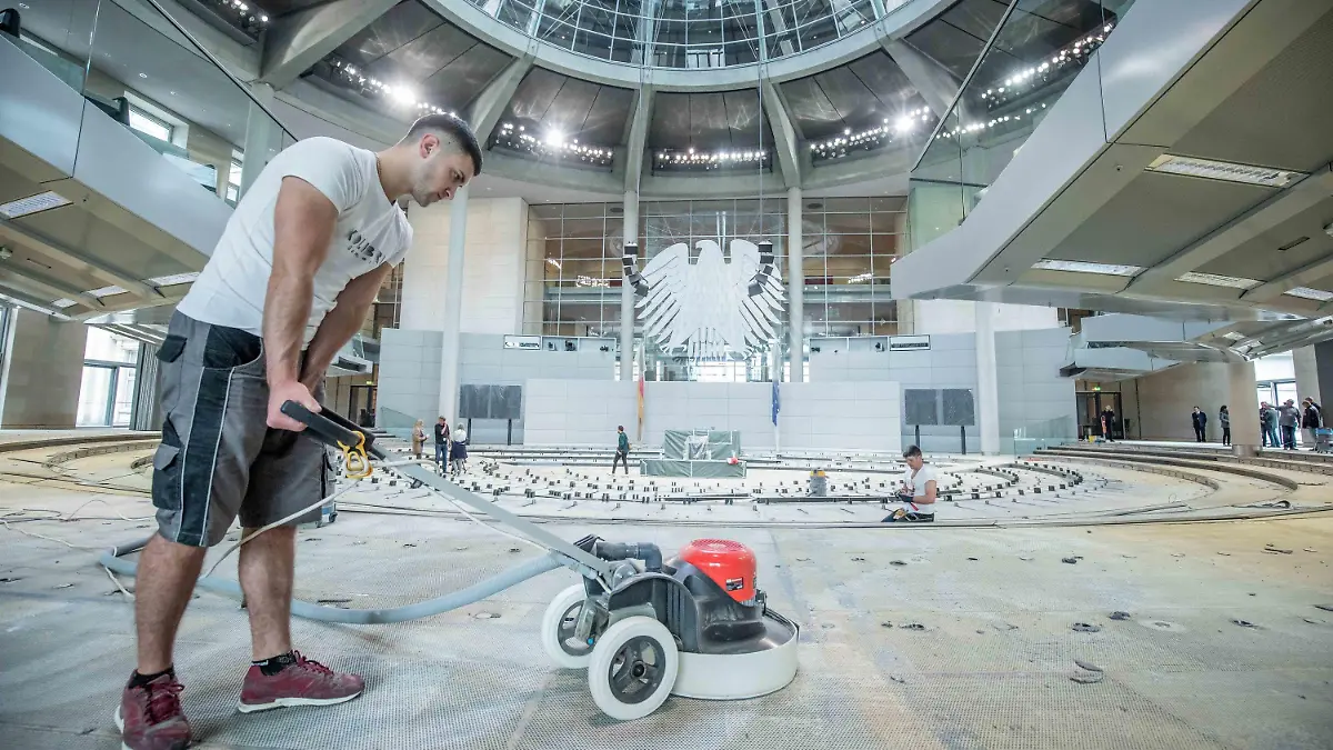 08.07.2019, Berlin: Handwerker entfernen die Kleberreste auf dem Boden im Plenarsaal im Deutschen Bundestag. In der Sommerpause wird der Teppich ausgetauscht, die Brandmeldeanlage erneuert und eine Induktionsschleife für Hörgeräteträger installiert. Foto: Michael Kappeler/dpa +++ dpa-Bildfunk +++