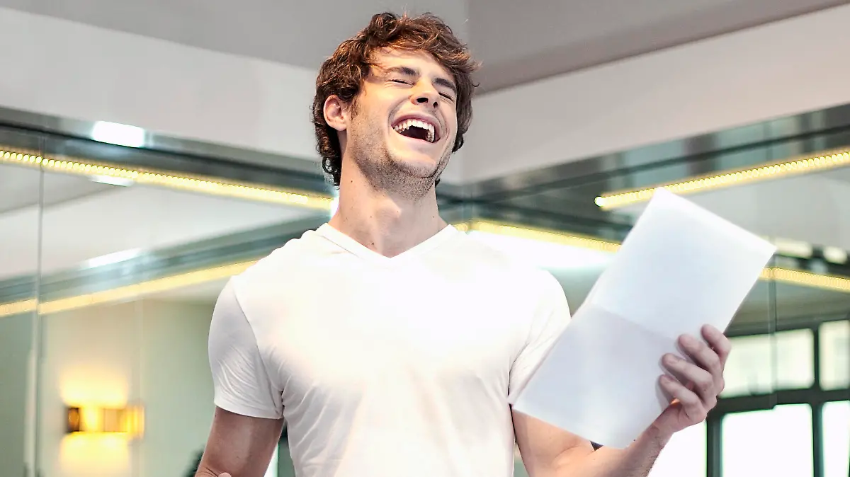 Happy man with letter laughing while holding coffee cup at kitchen || Modellfreigabe vorhanden