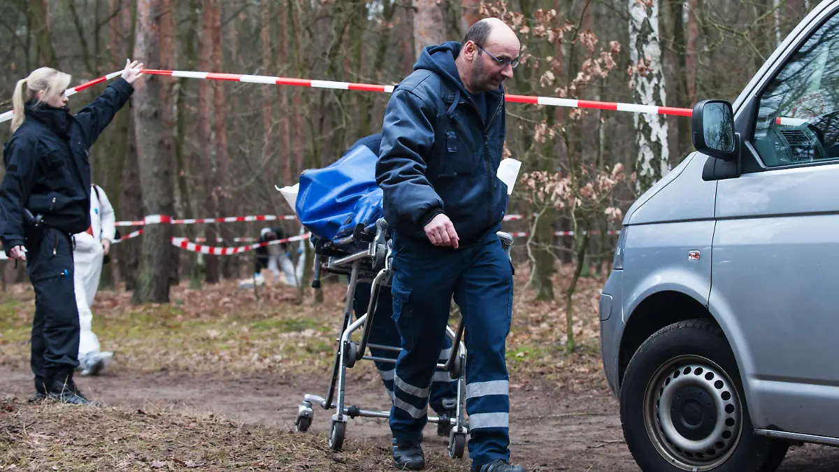 Mitarbeiter der Gerichtsmedizin bringen am 23.01.2015 in Berlin in einem Waldstück an der Bärenlauchstraße eine Leiche zu ihrem Fahrzeug. Dort hatten am Morgen Spaziergänger die Leiche einer jungen Frau gefunden. Die Polizei geht von einem Gewaltverbrechen aus. Kriminaltechniker sind an der Fundstelle, die weiträumig abgesperrt wurde. Foto: Paul Zinken/dpa (zu dpa "Schwangere Frau in Berlin bei lebendigem Leib verbrannt" am 22.01.2015) +++(c) dpa - Bildfunk+++
