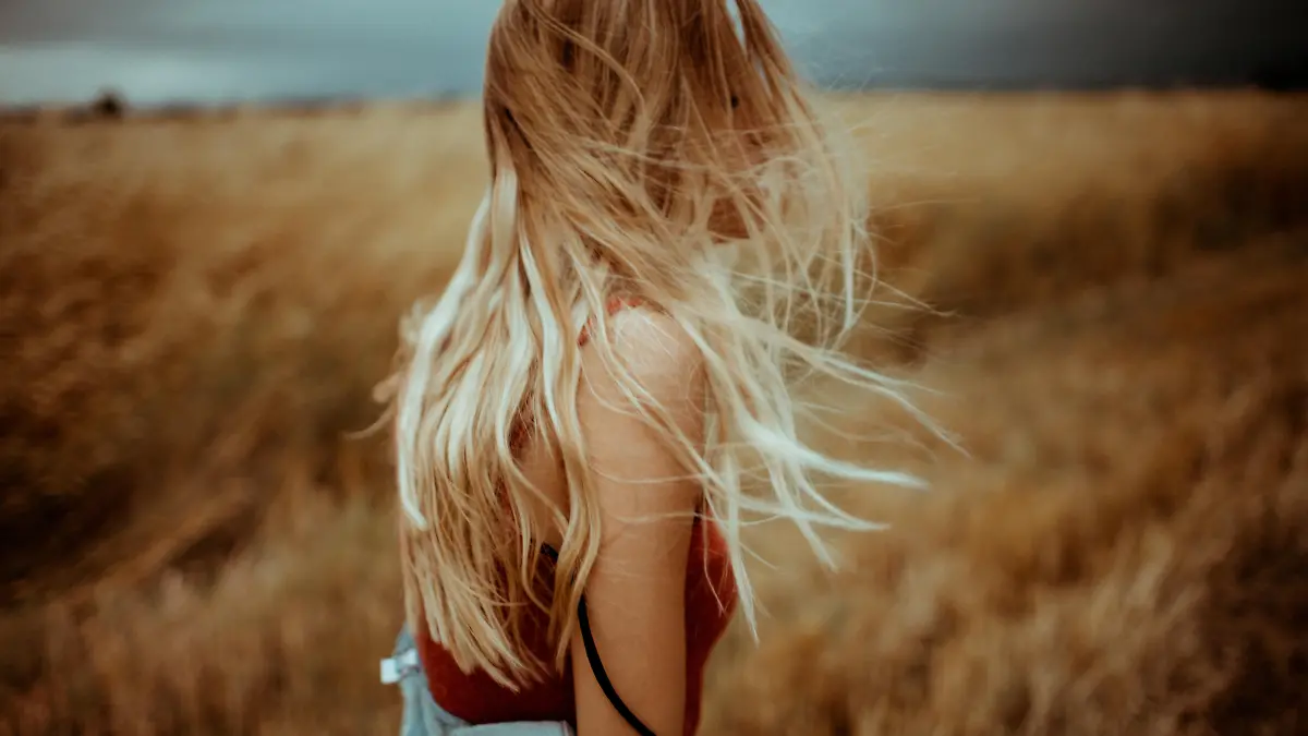 Photo of a young woman running in the middle of a wheat field, feeling free and happy