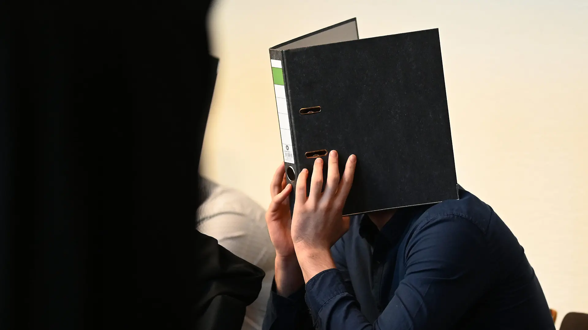 18.05.2019, Baden-Württemberg, Freiburg: Einer von elf Angeklagten sitzt vor dem Prozessbeginn im Gerichtssaal im Landgericht. Elf Männer sollen laut Anklage Mitte Oktober 2018 eine 18-Jährige nachts in einem Gebüsch vor einer Diskothek vergewaltigt haben. Foto: Patrick Seeger/dpa +++ dpa-Bildfunk +++