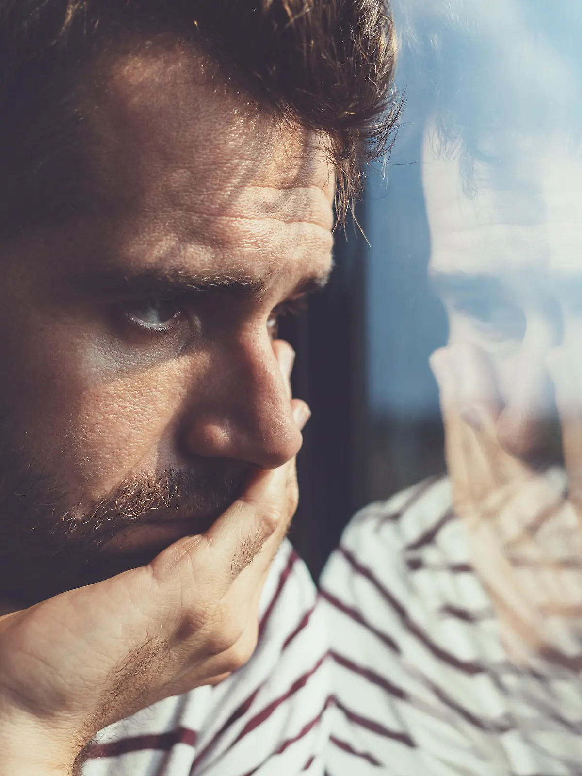 Sad young man looking through the window