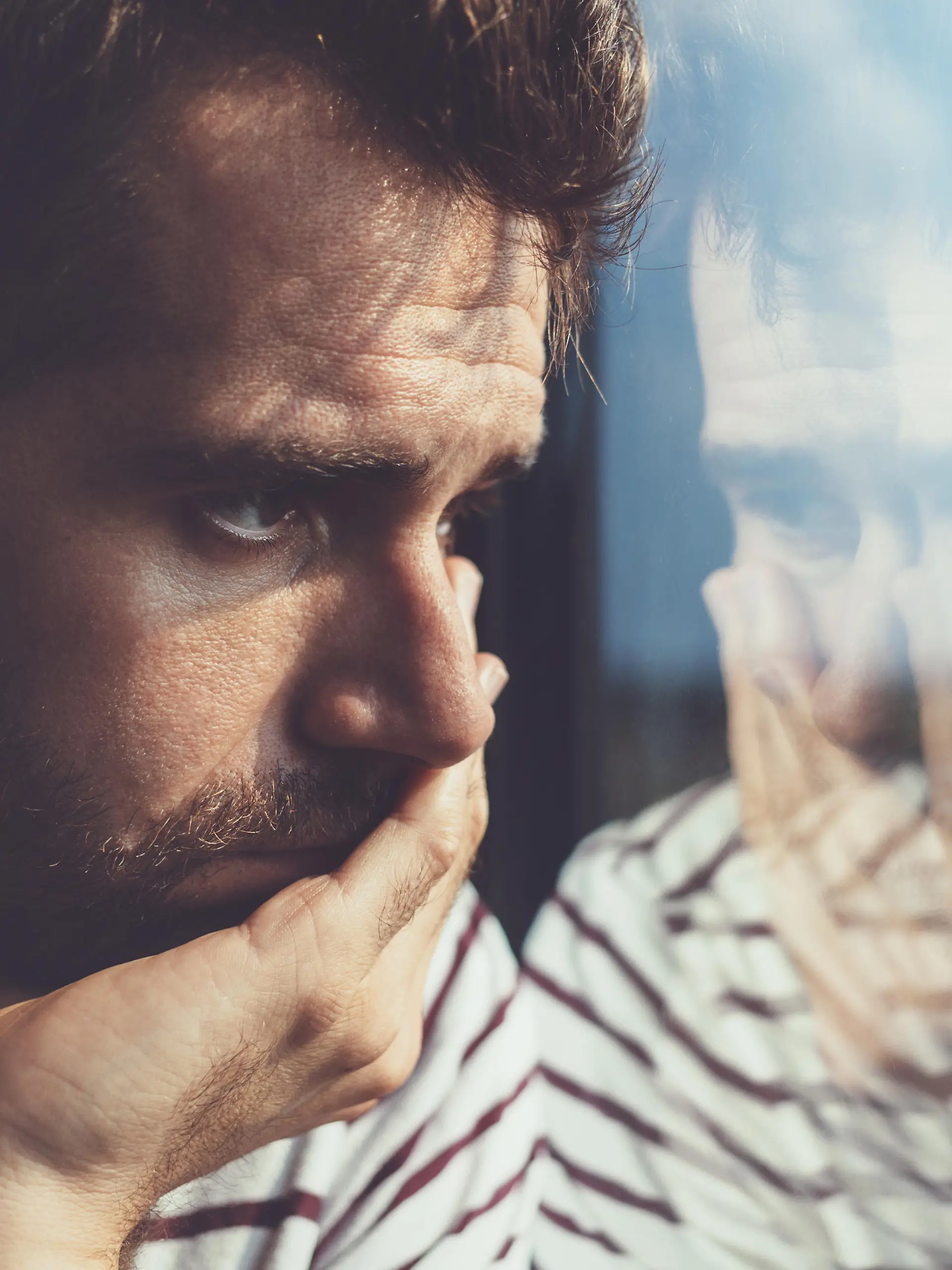 Sad young man looking through the window