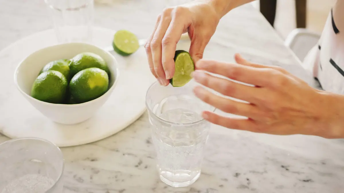 A woman squeezing fresh limes into a glass of water. A woman squeezing fresh limes into a glass of water. PUBLICATIONxINxGERxSUIxAUTxHUNxONLY 22164