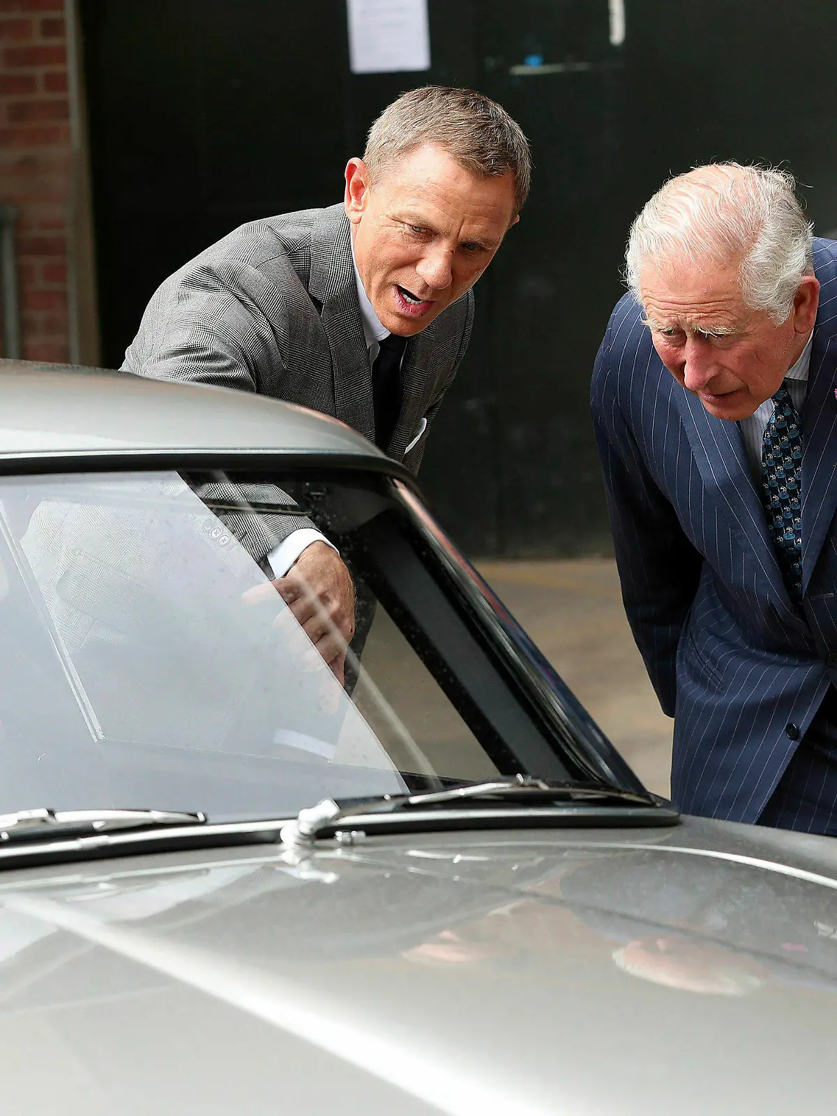 20.06.2019, Großbritannien, Pinewood Studios: Charles (r), britischer Prinz von Wales, steht mit dem Schauspieler Daniel Craig bei einem Besuch des Sets des 25. James-Bond-Films in den Pinewood Studios hinter dem Aston Martin DB5 Bond-Auto aus einem Bond-Film, während Craig spricht. Foto: Chris Jackson/PA/dpa +++ dpa-Bildfunk +++