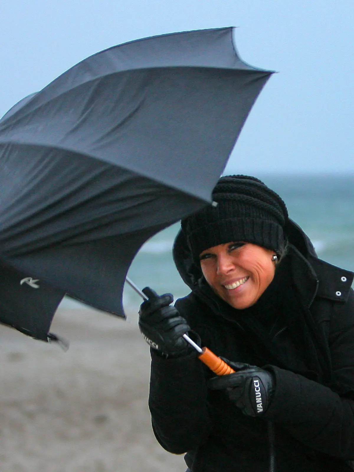 Mit einem vom Wind in Mitleidenschaft gezogenen Regenschirm ist eine Spaziergängerin am Mittwoch (18.11.2009) am Strand des Ostseebades Warnemünde unterwegs. Mit viel Regen und stürmischem Wind herrscht an der Osteee klassisches Schmuddelwetter. Foto: Bernd Wüstneck dpa/lmv  +++(c) dpa - Bildfunk+++