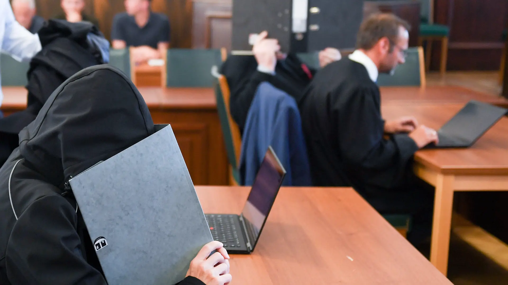 19.06.2019, Hessen, Darmstadt: Ein 59-jähriger Mann (r) und seine 47-jährige Ehefrau verbergen vor der Urteilsverkündung im Gerichtssaal des Landgerichts die Gesichter mit Aktenordnern. Wegen Mordes an seinen beiden Kindern ist der Vater zu lebenslanger Haft verurteilt worden, die Mutter zu 12 Jahren Haft wegen Beihilfe zum Mord. Laut Anklage hat das insolvente Zahnärzte-Ehepaar in der Nacht zum 31. August 2018 das Mädchen und seinen Bruder gemeinsam erschlagen und erstochen. Danach sollen die Eltern Feuer im Haus gelegt und erfolglos versucht haben, sich mit Autoabgasen selbst zu töten. Foto: Arne Dedert/dpa +++ dpa-Bildfunk +++
