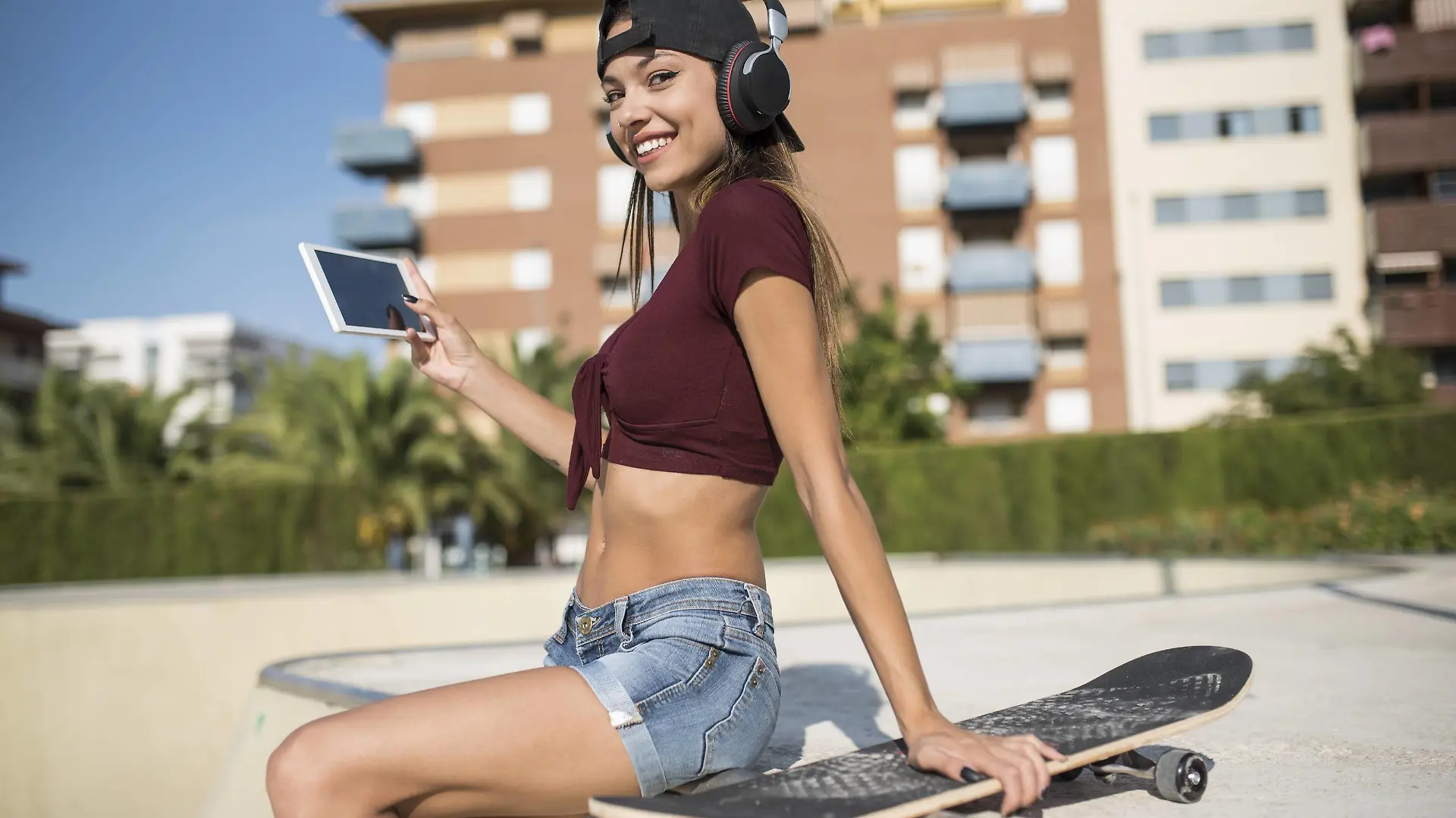 Young pretty woman sitting on wall of skatepark, listen music, using digital tablet model released Symbolfoto PUBLICATIONxINxGERxSUIxAUTxHUNxONLY JASF01947  
