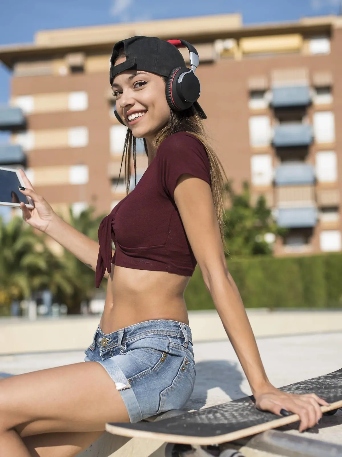 Young pretty woman sitting on wall of skatepark, listen music, using digital tablet model released Symbolfoto PUBLICATIONxINxGERxSUIxAUTxHUNxONLY JASF01947  