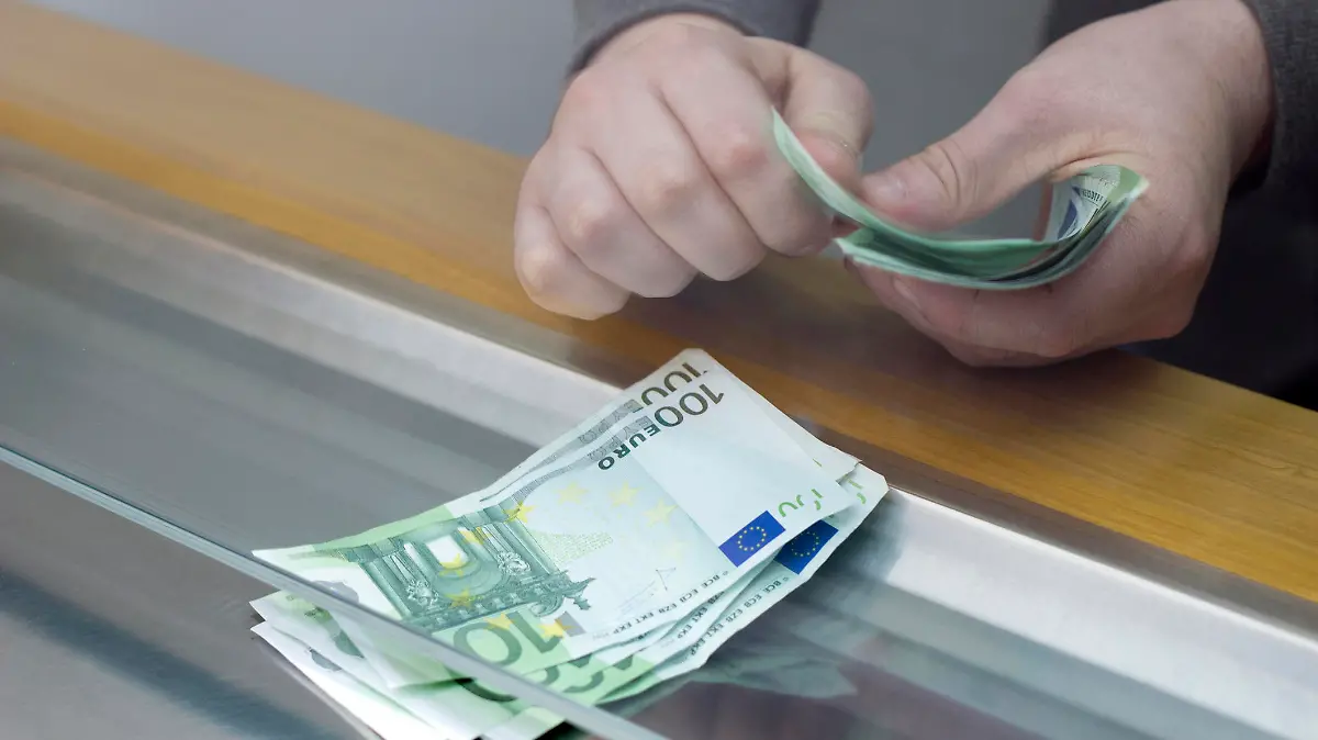 Bankkunde hebt Geld am Schalter ab.