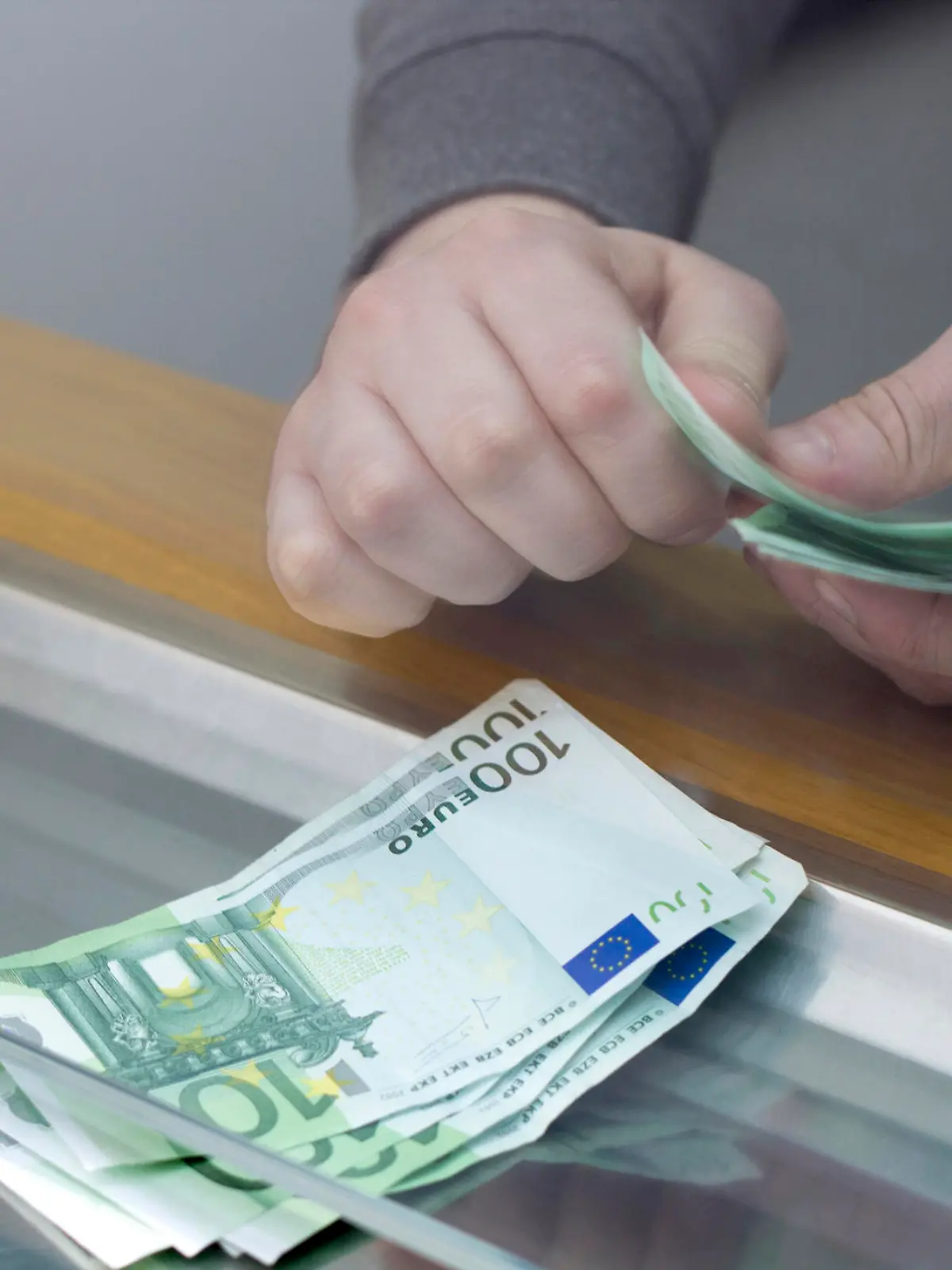 Bankkunde hebt Geld am Schalter ab.