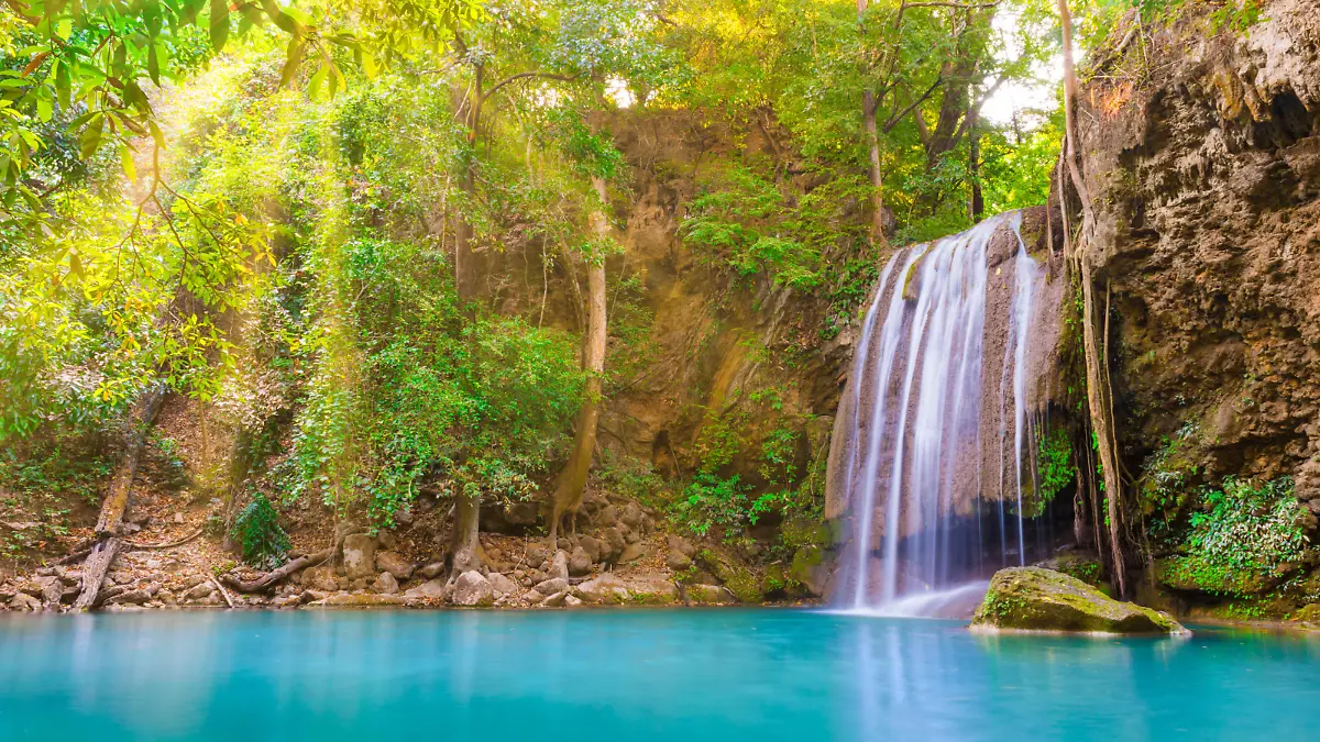 Tropical landscape with beautiful waterfall, wild rainforest with green foliage and flowing water. Erawan National park, Kanchanaburi, Thailand