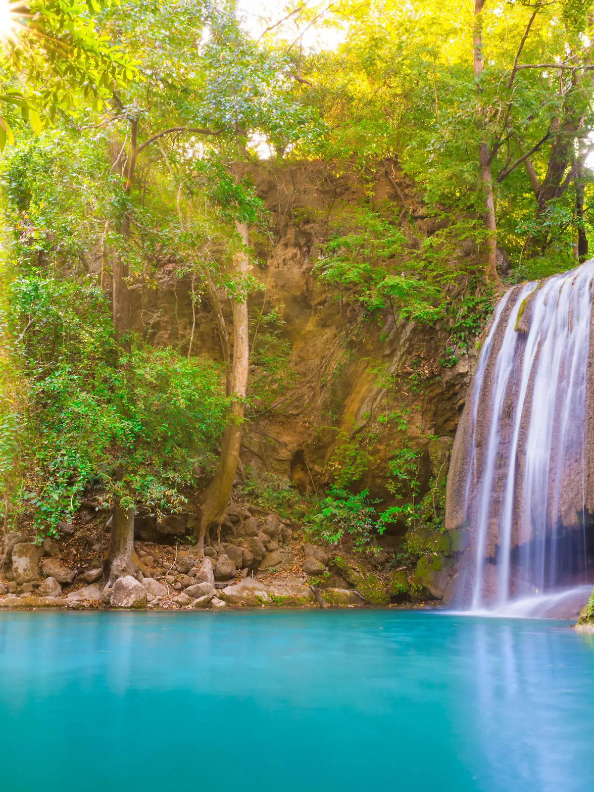Tropical landscape with beautiful waterfall, wild rainforest with green foliage and flowing water. Erawan National park, Kanchanaburi, Thailand