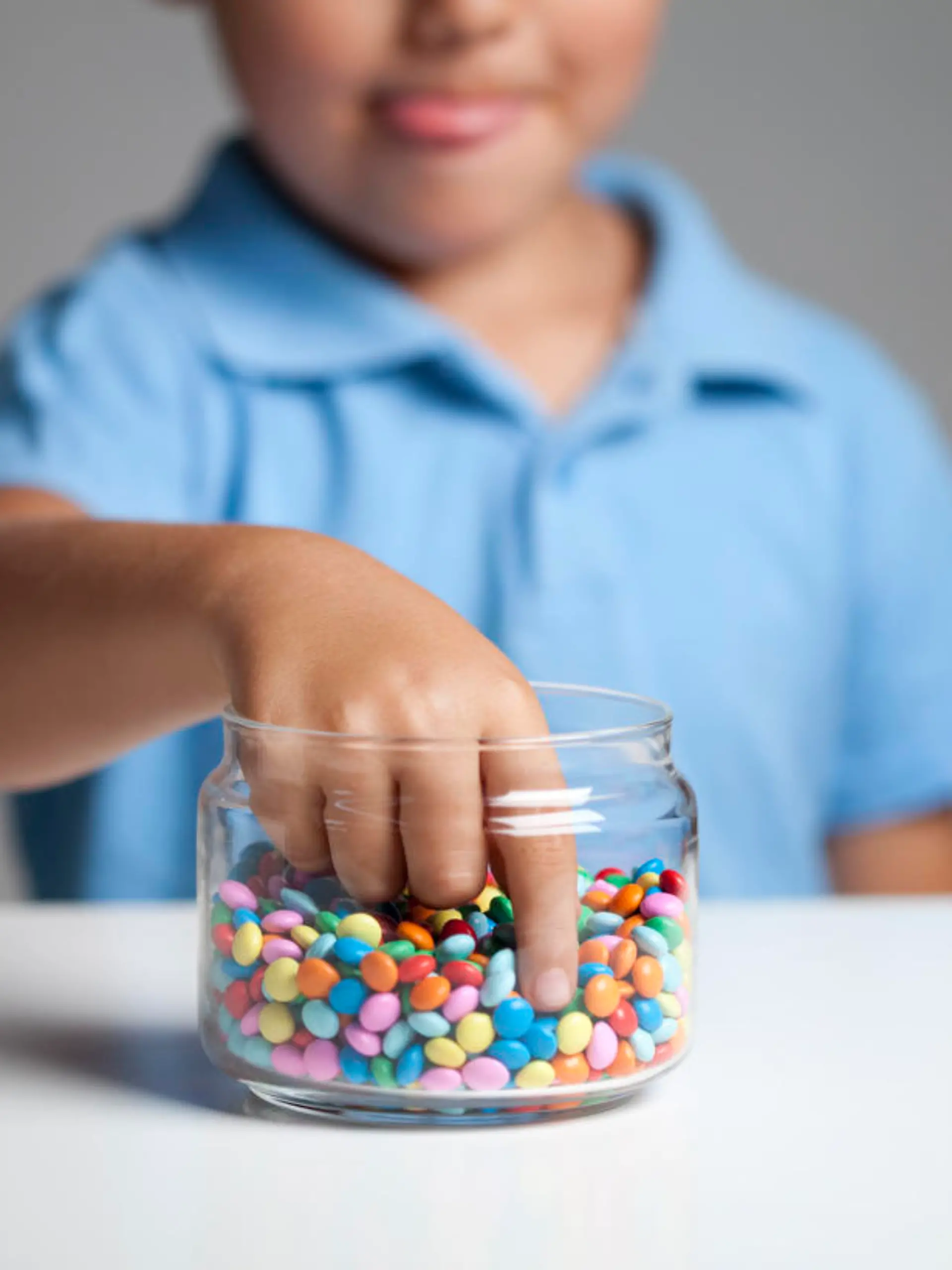 Little boy licking his lips while taking candy from the candy jar.