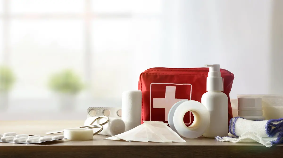 Basic home kit for cures in domestic accidents on a wooden table in a room. Horizontal composition. Front view.