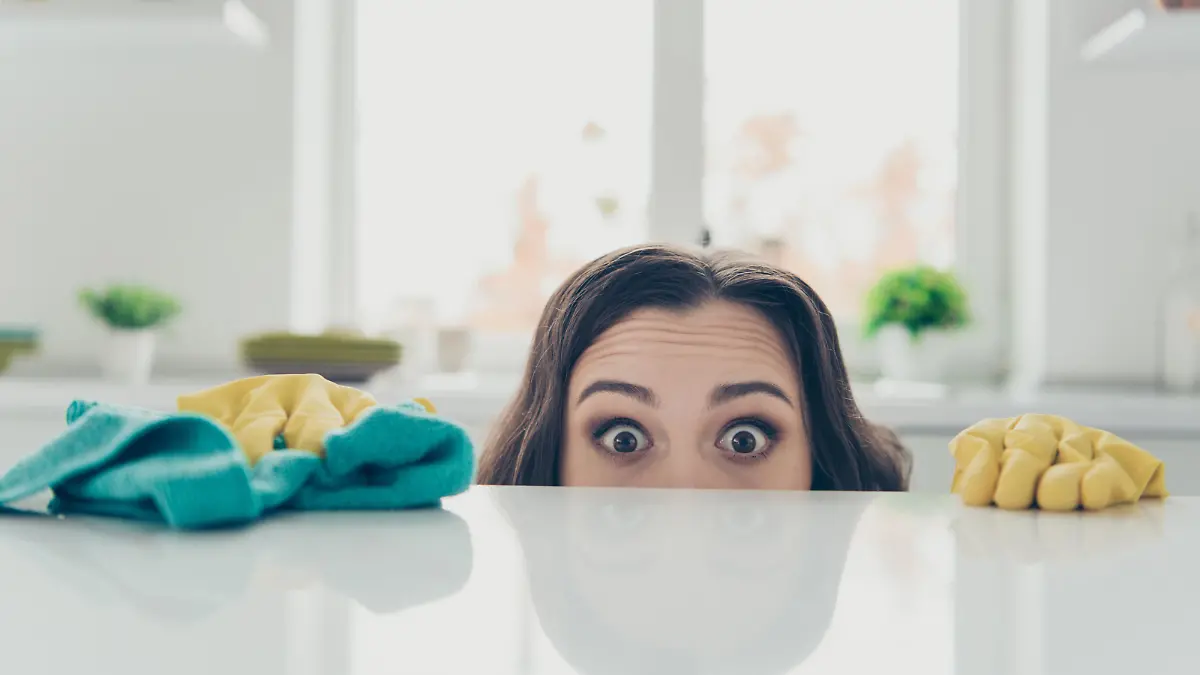 Portrait of her she nice cute lovely beautiful girlish funny shocked wavy-haired house-wife hiding behind shine glossy table in modern light white interior indoors