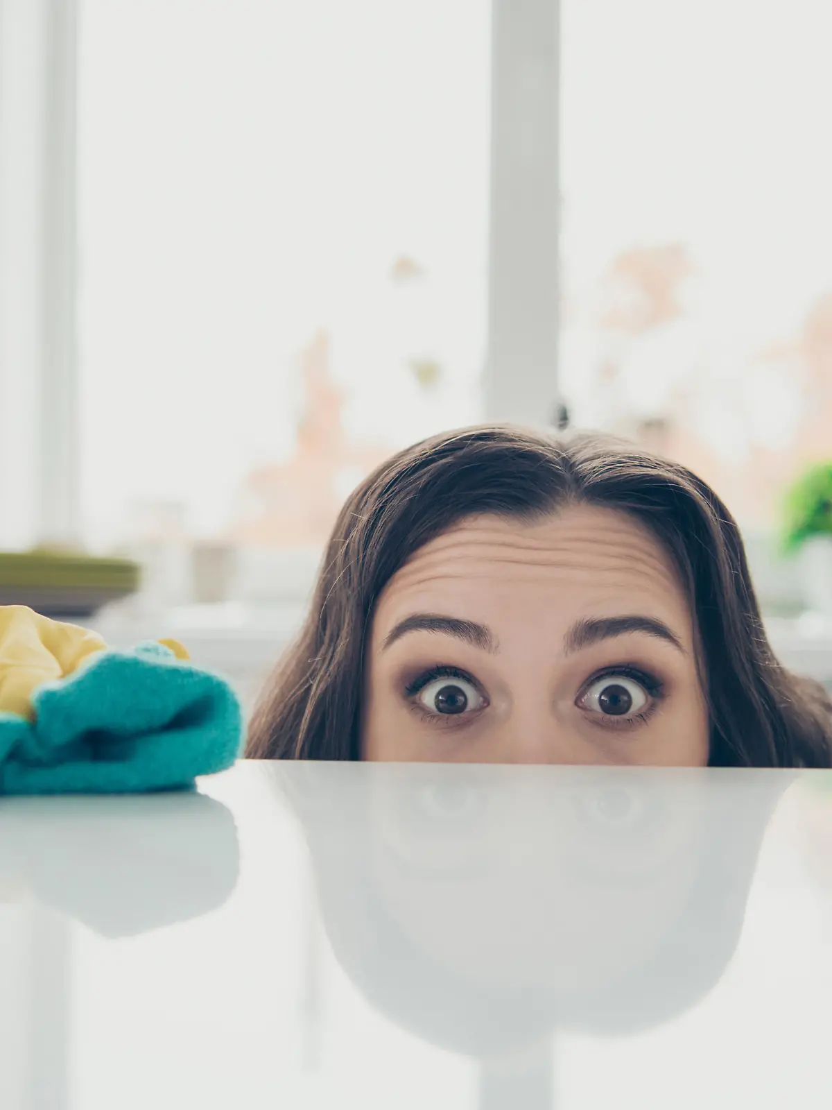 Portrait of her she nice cute lovely beautiful girlish funny shocked wavy-haired house-wife hiding behind shine glossy table in modern light white interior indoors