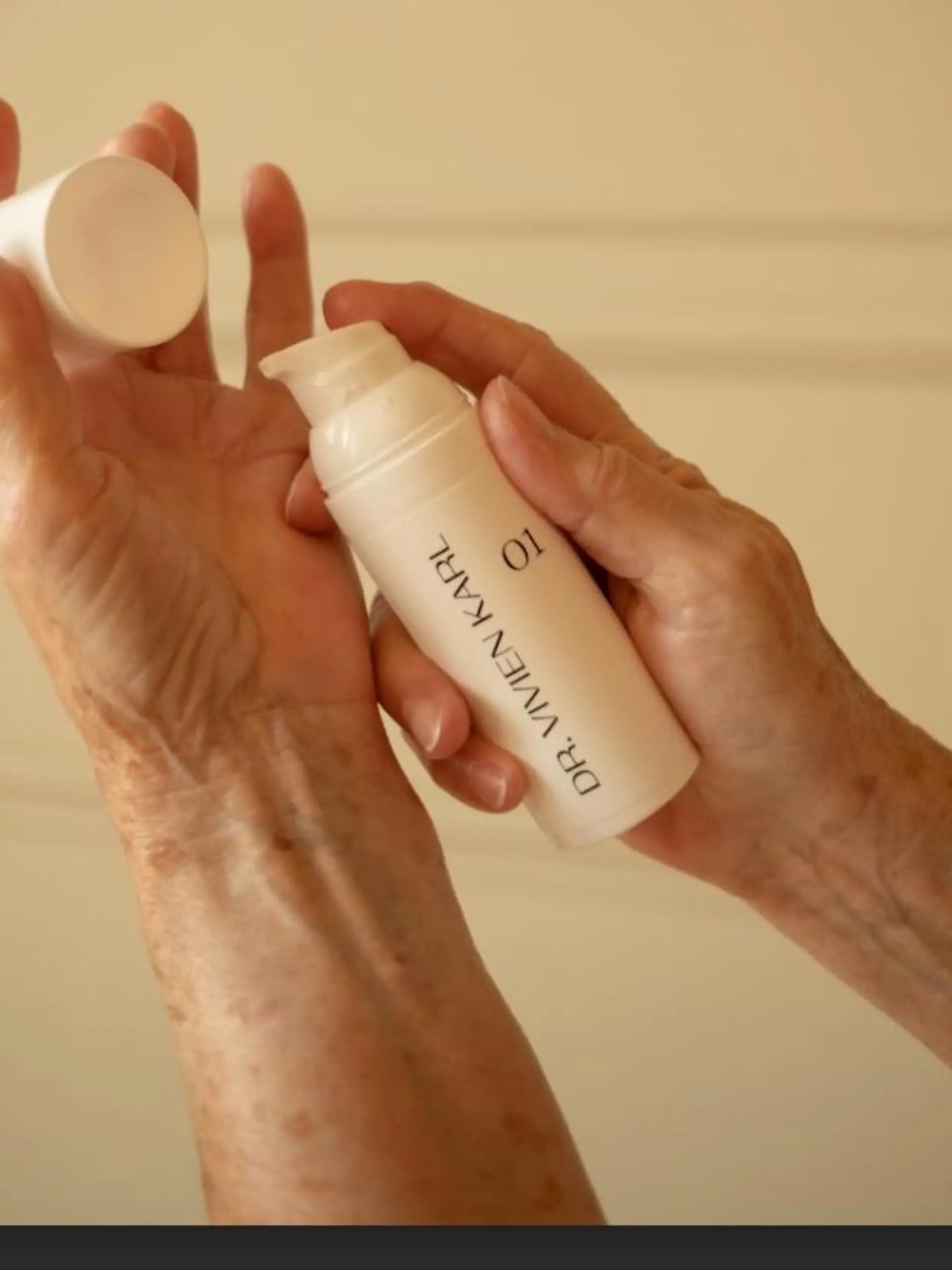 Hände halten Spender mit Creme von Dr. Vivien Karl