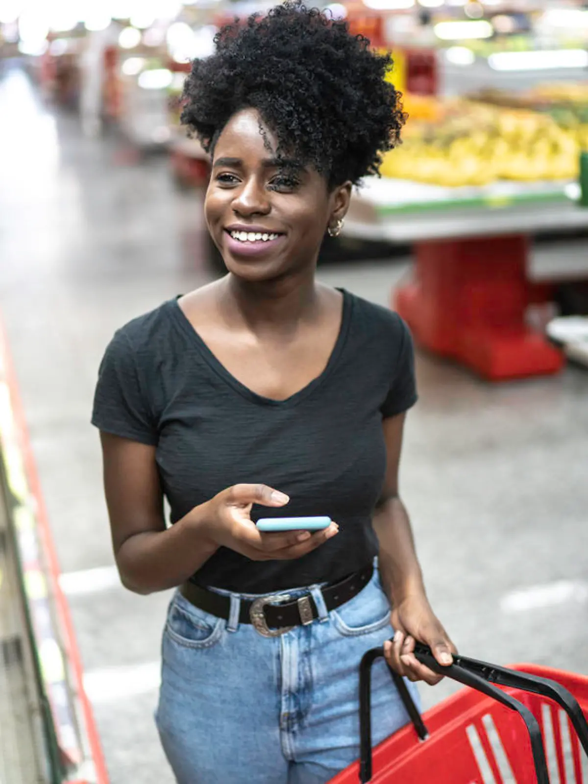 Young woman using mobile phone and choosing product in supermarket