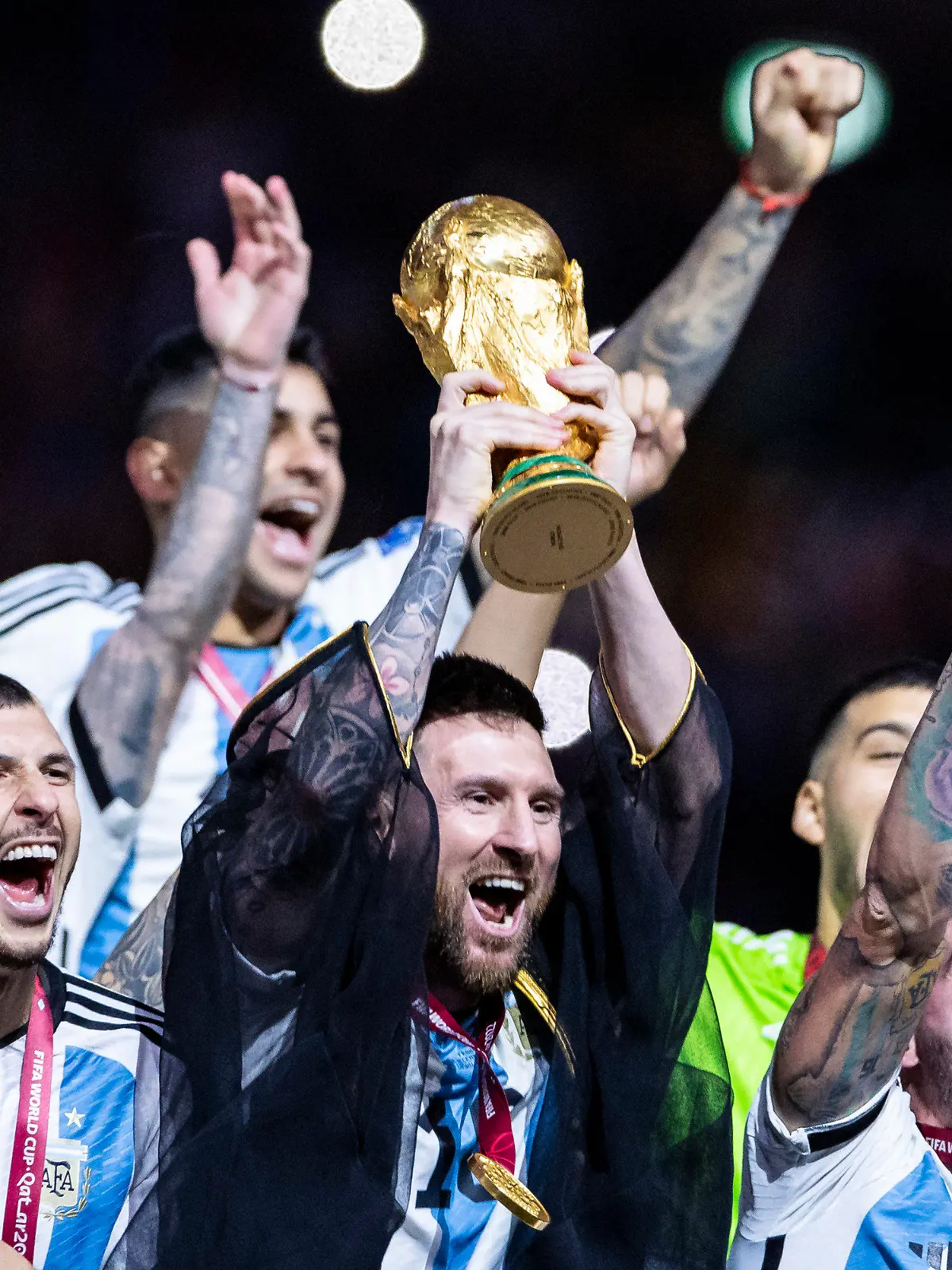 ARCHIV - 18.12.2022, Katar, Lusail: Fußball: WM, Argentinien - Frankreich, Finalrunde, Finale, Lusail Stadion, Argentiniens Lionel Messi jubelt mit WM - Pokal und seiner Mannschaft über den gewinn der Weltmeisterschaft. Am Montag ist Messi Favorit auf die Auszeichnung als Weltfußballer 2022.  (zu dpa: «Kein Umhang, kein Hahn: Messi vor nächster Weltfußballer-Krönung») Foto: Tom Weller/dpa +++ dpa-Bildfunk +++