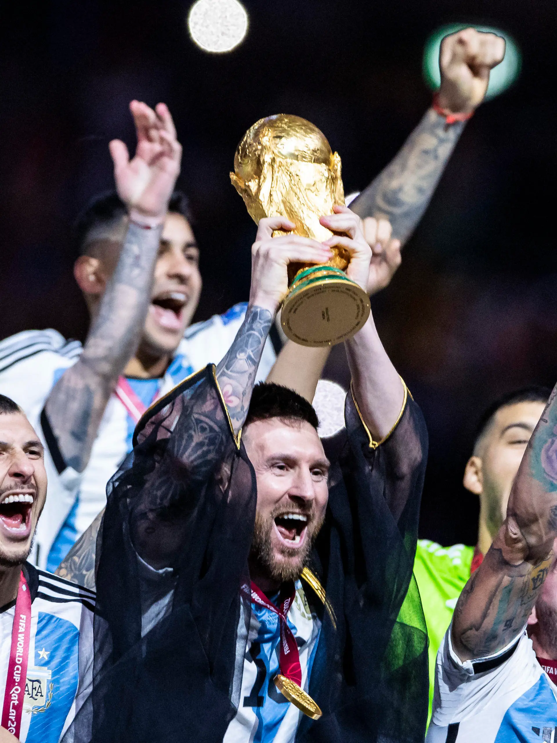 ARCHIV - 18.12.2022, Katar, Lusail: Fußball: WM, Argentinien - Frankreich, Finalrunde, Finale, Lusail Stadion, Argentiniens Lionel Messi jubelt mit WM - Pokal und seiner Mannschaft über den gewinn der Weltmeisterschaft. Am Montag ist Messi Favorit auf die Auszeichnung als Weltfußballer 2022.  (zu dpa: «Kein Umhang, kein Hahn: Messi vor nächster Weltfußballer-Krönung») Foto: Tom Weller/dpa +++ dpa-Bildfunk +++