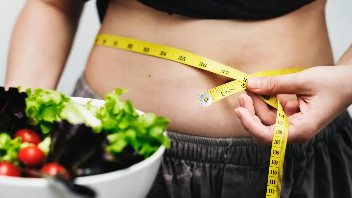 Frau mit Salat und Maßband um den Bauch
