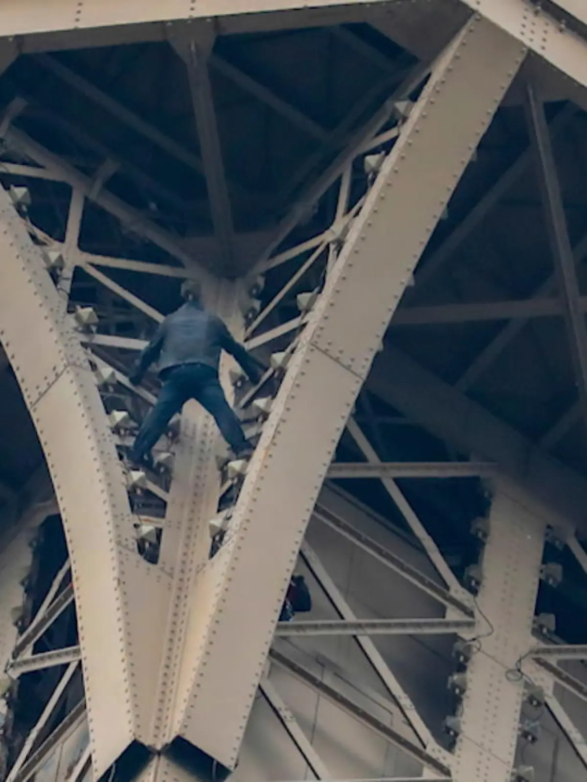 Bild zu: "Mann klettert auf Eiffelturm"