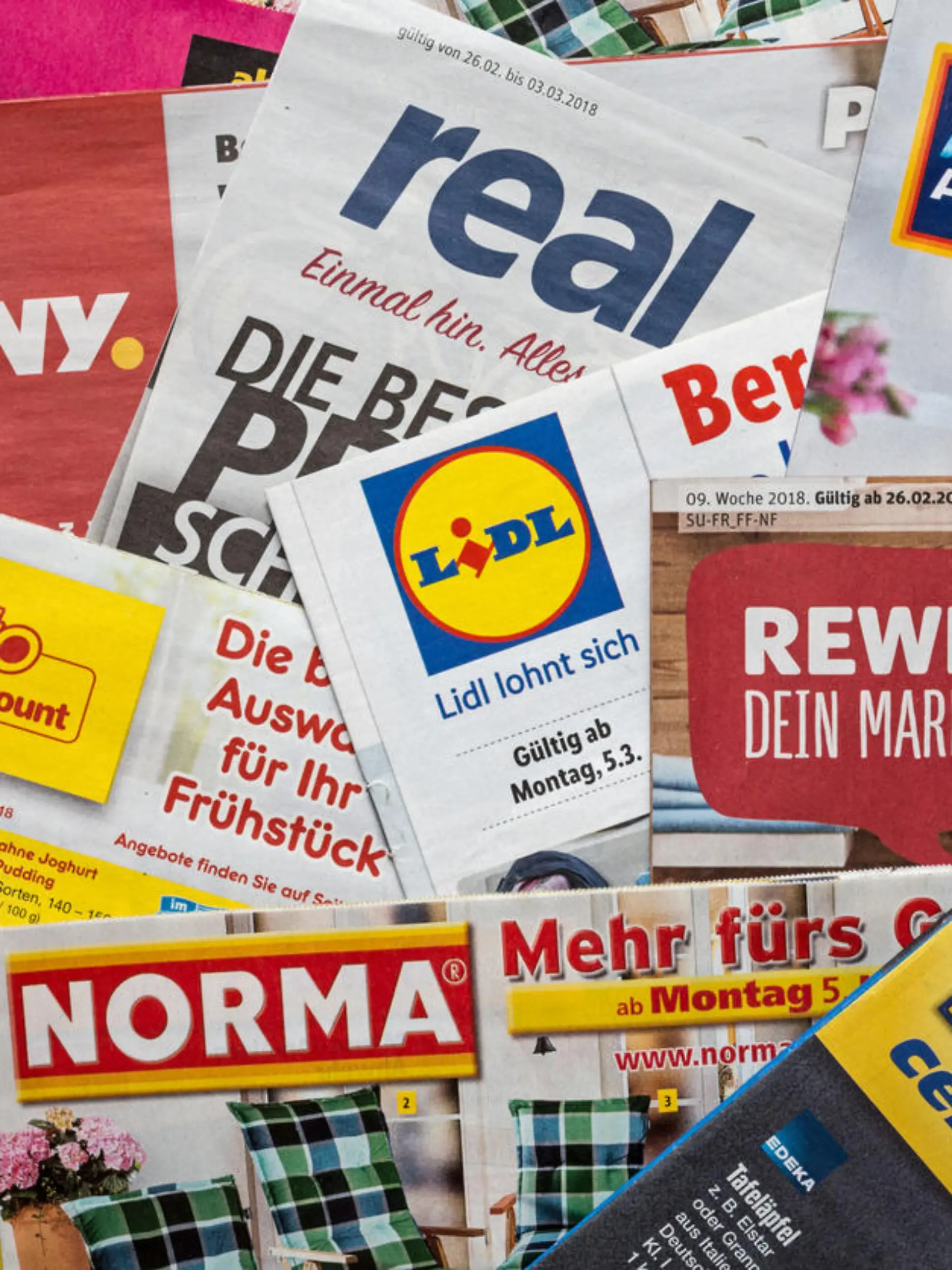 Amberg, Germany - February 26, 2018: Advertising leaflets of some German supermarket chains. Logos and brands are visible. Lidl, Aldi Süd, Penny Markt, Norma, Netto, Edeka, Real, Rewe.