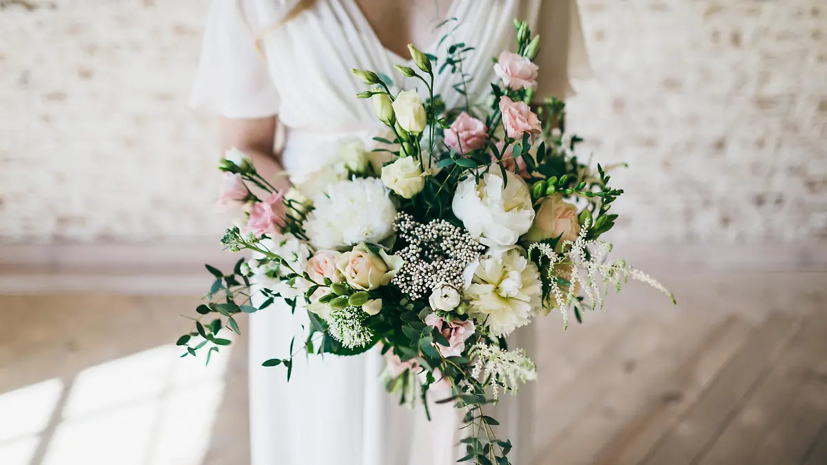 Gorgeous bouquet of white and pink flowers in the hands of the charming bride in a white dress. Artwork. Indoors