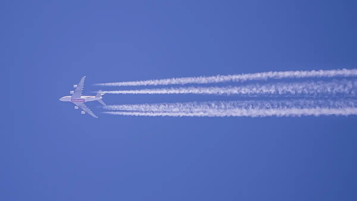 Kondensstreifen eines Flugzeugs der Fluggesellschaft Qatar Airways sind am blauen Himmel zu sehen.