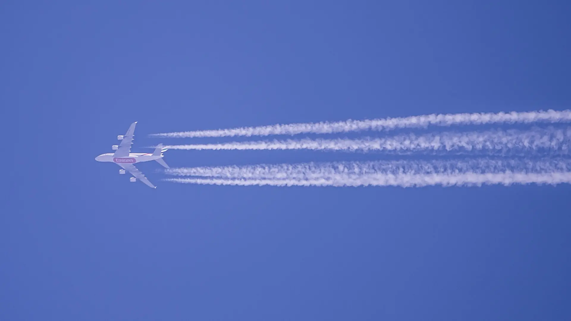 Kondensstreifen eines Flugzeugs der Fluggesellschaft Qatar Airways sind am blauen Himmel zu sehen.