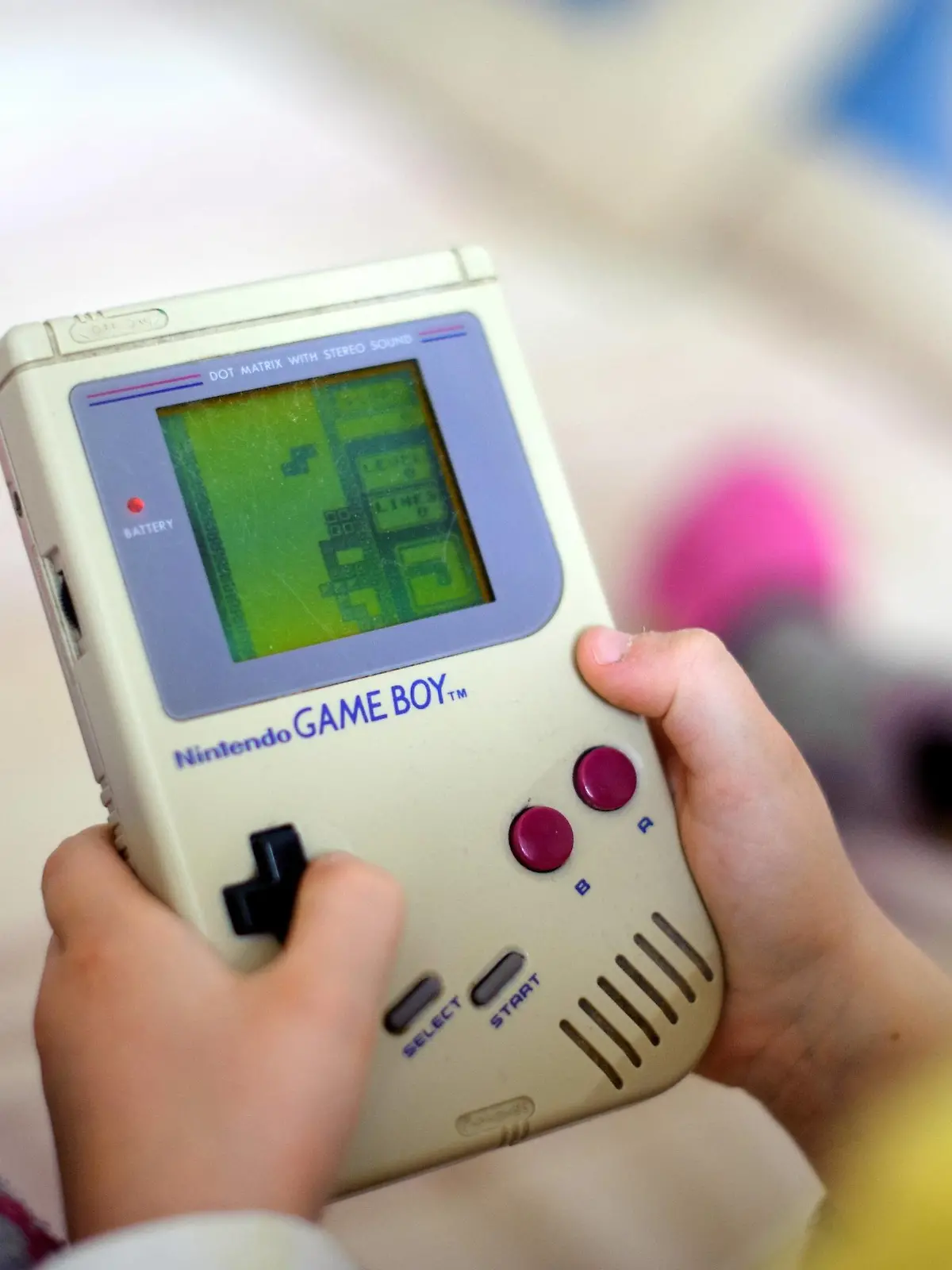Ein Kind spielt auf einem originalen Game Boy das Spiel Tetris .  