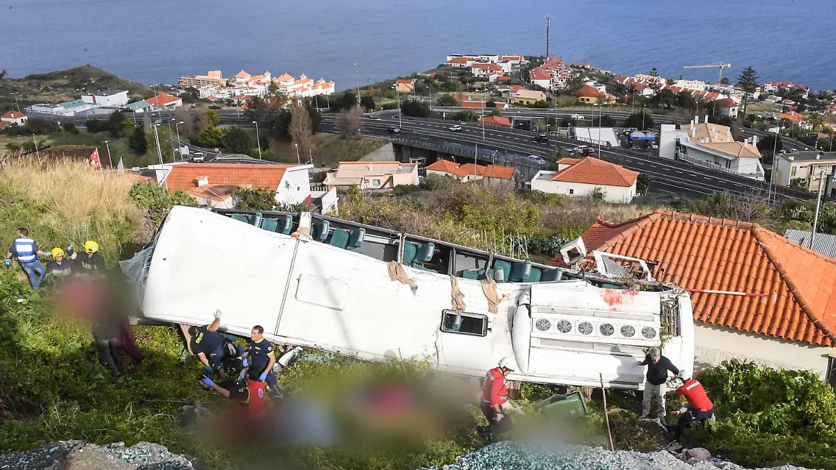 17.04.2019, Portugal, Canico: Rettungskräfte stehen nach einem schweren Busunglück auf der portugiesischen Ferieninsel Madeira an dem Bus. Bei dem Busunglück auf der portugiesischen Atlantikinsel Madeira sind 29 Menschen ums Leben gekommen. Unter den Opfern sind nach bisherigen Erkenntnissen wahrscheinlich viele deutsche Urlauber. Foto: Rui Silva/Aspress/Global Imagens/dpa - ACHTUNG: Opfer wurden gepixelt +++ dpa-Bildfunk +++