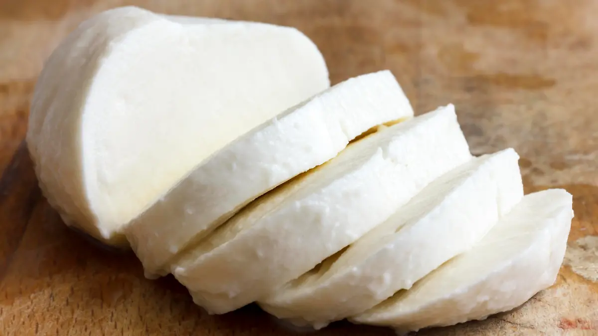 Single ball of mozzarella cheese sliced and isolated on rustice wood.