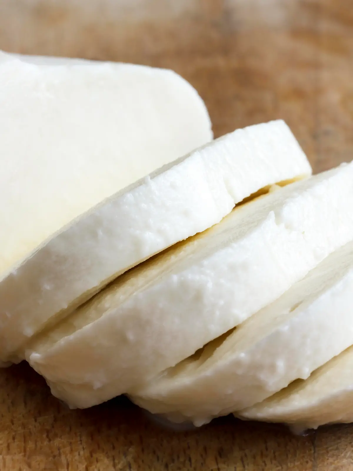 Single ball of mozzarella cheese sliced and isolated on rustice wood.