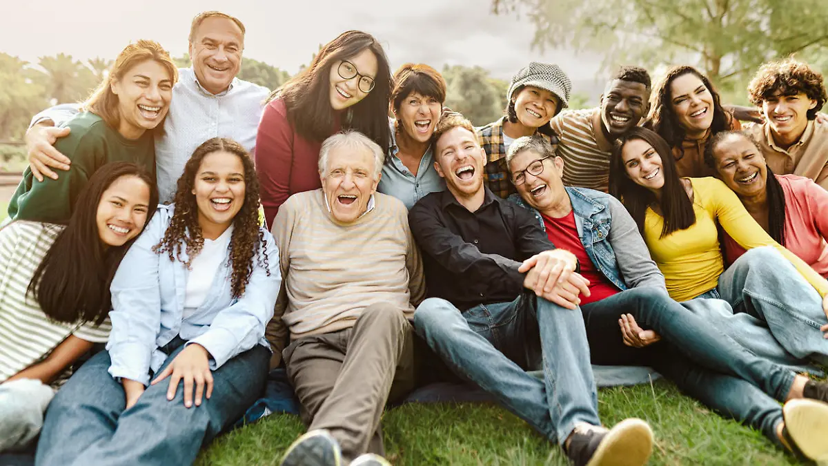 Happy multigenerational people having fun sitting on grass in a public park