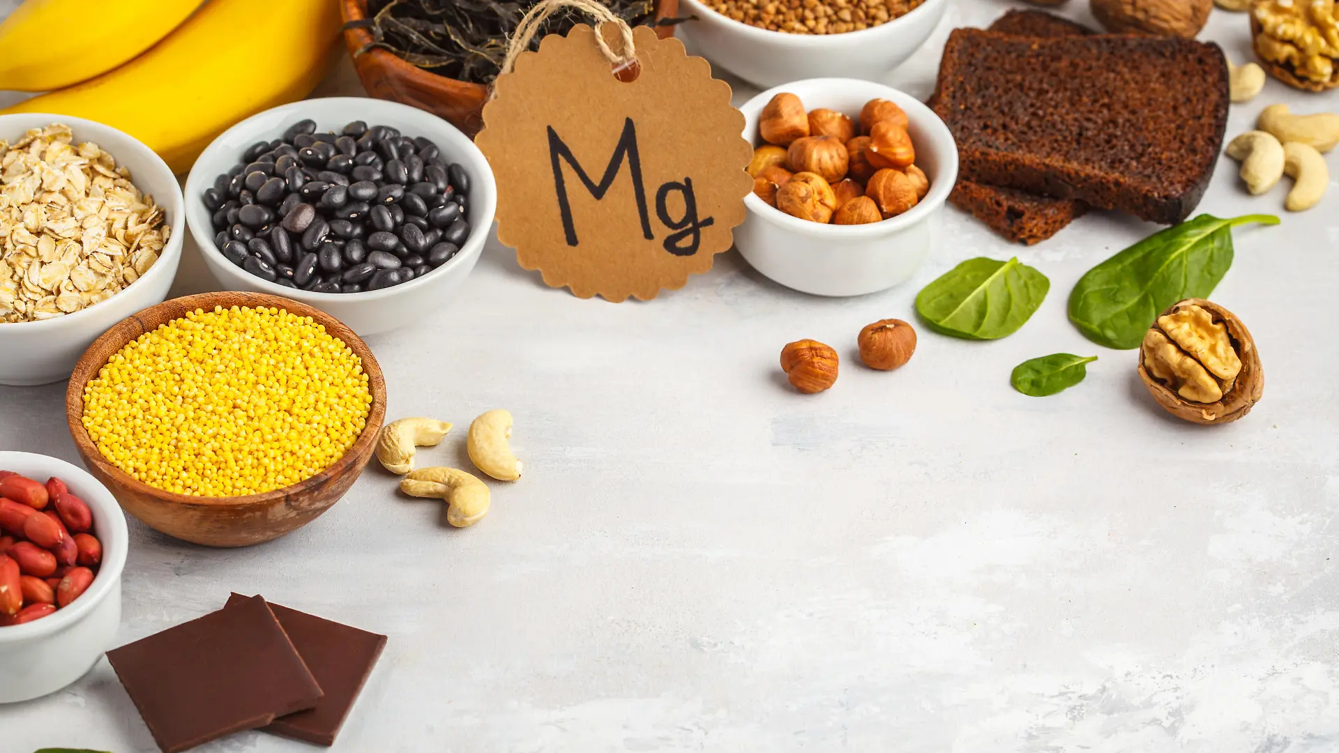 Healthy food nutrition dieting concept. Assortment of high magnesium sources. Banana chocolate spinach, buckwheat, nuts, beans, oat.