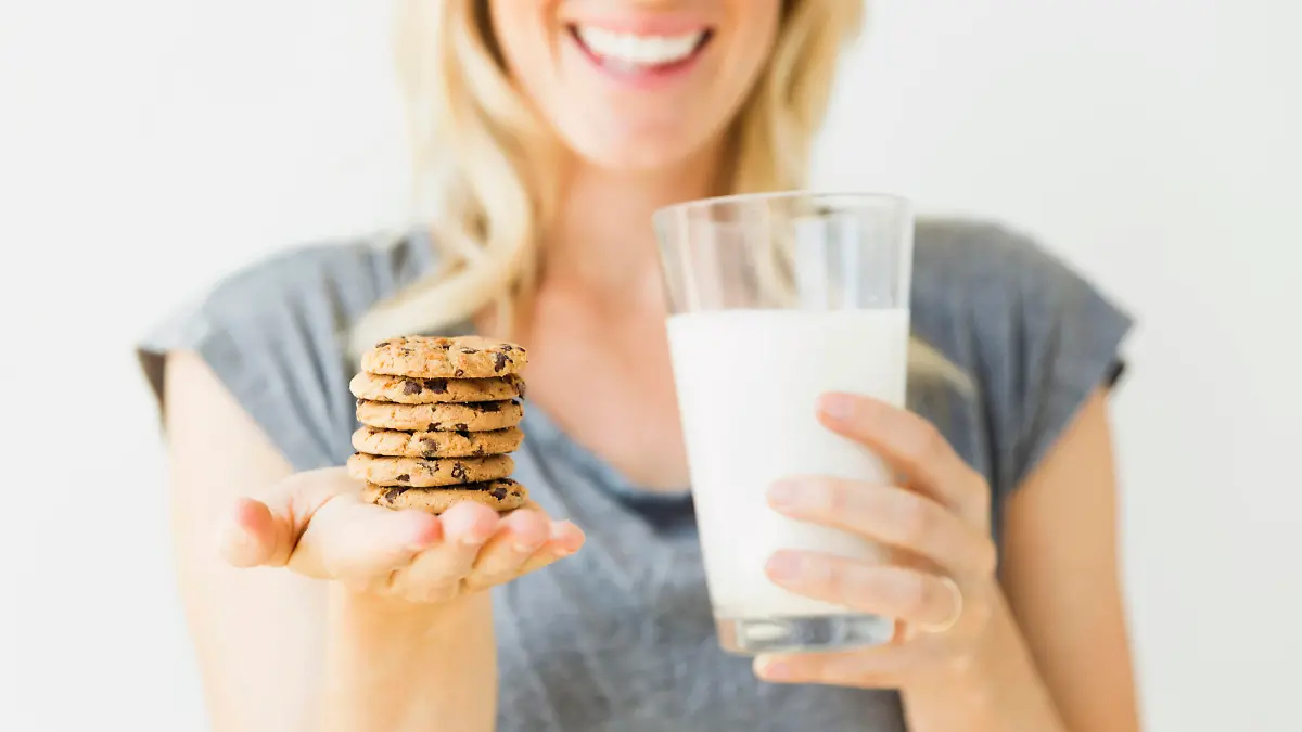 , Studio portrait of blonde woman holding glass of milk and cookies Keine Weitergabe an Drittverwerter.